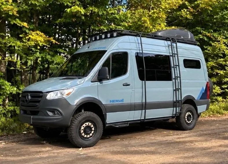 Fourgon aménagé Hervé G2 sur Mercedes-Benz Sprinter, stationné en forêt avec sa porte coulissante ouverte.