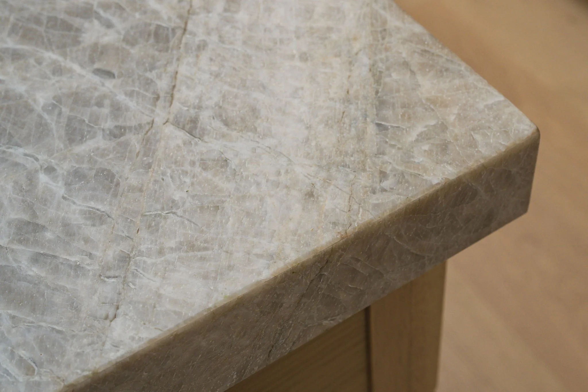 Close-up of a marble or stone countertop with a light, beige color and veining patterns.
