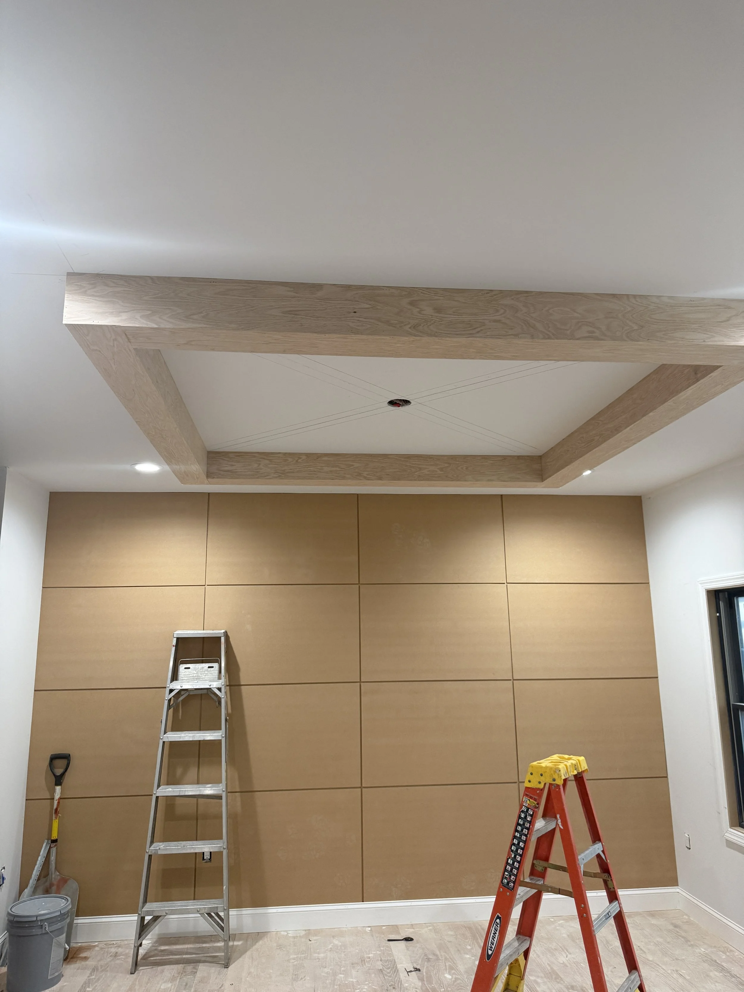 Interior room under renovation with a wooden frame on the ceiling, two ladders, and construction tools.