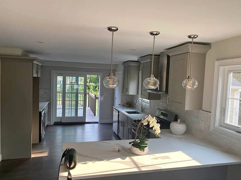 Modern kitchen with pendant lights, gray cabinets, and a sliding glass door leading outside.