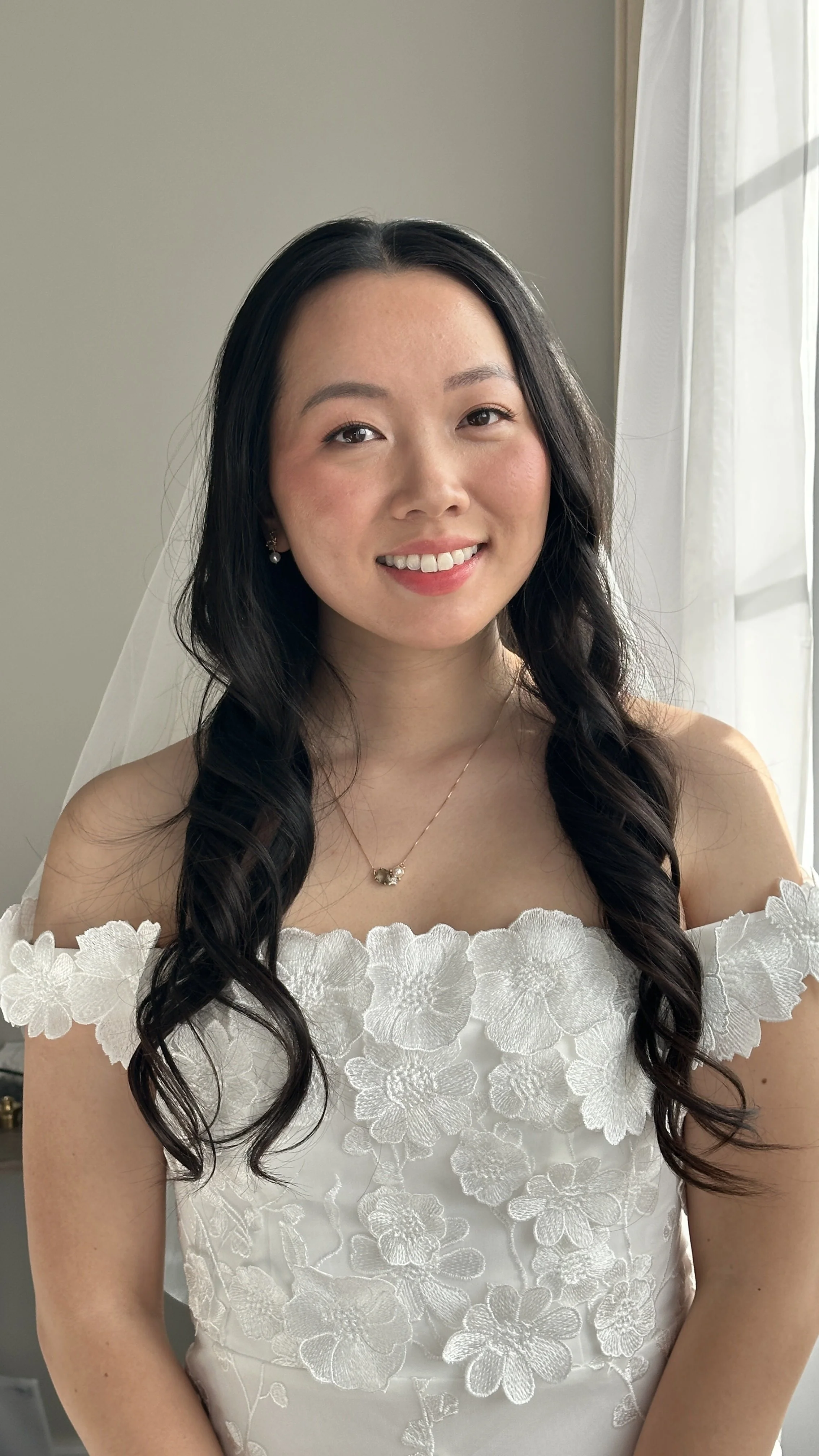 Bride smiling in natural bridal makeup and romantic soft waves, a look that feels beautifully her.