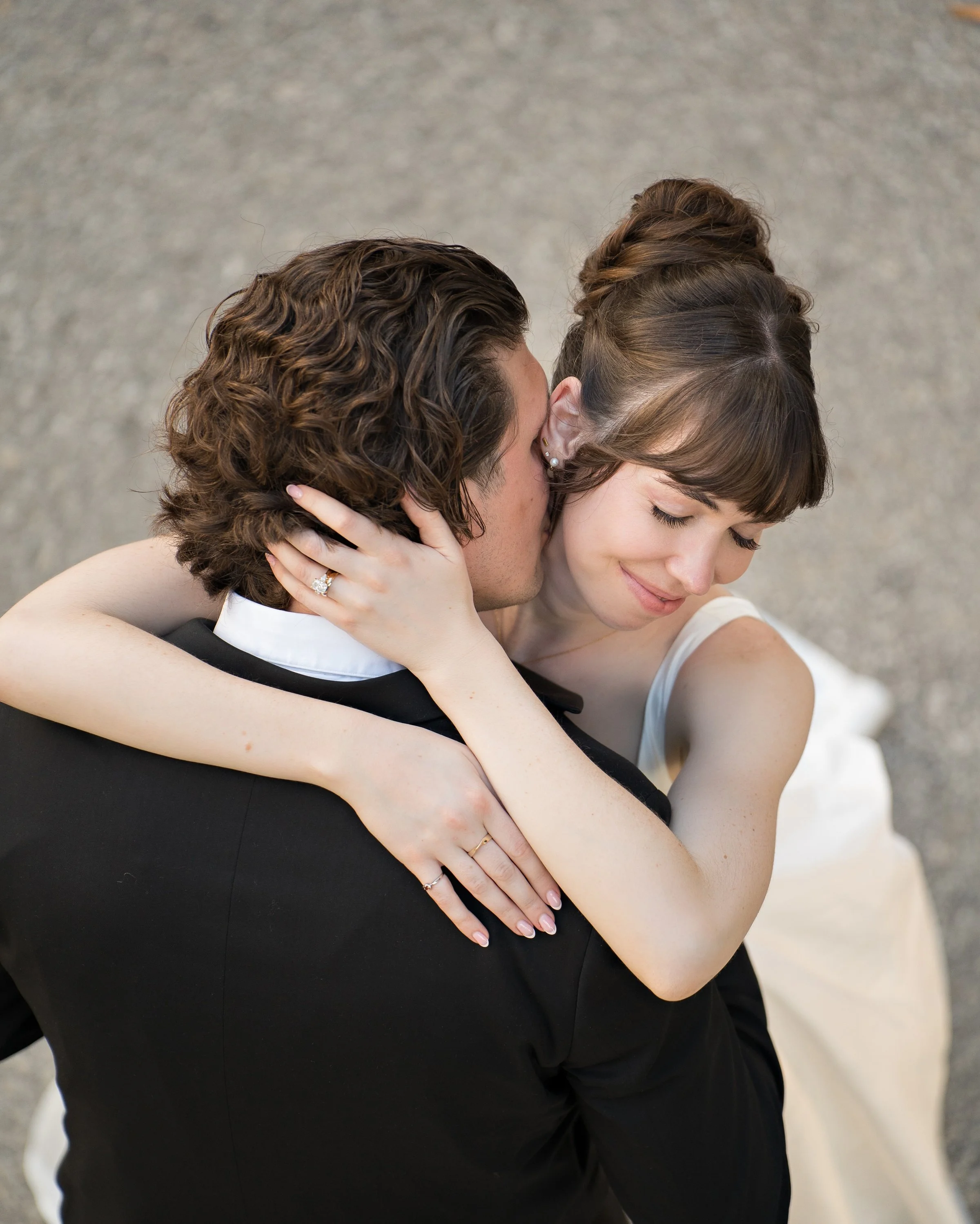 Bride wearing a princess-inspired bridal updo with soft, face-framing bangs and delicate tendrils.
