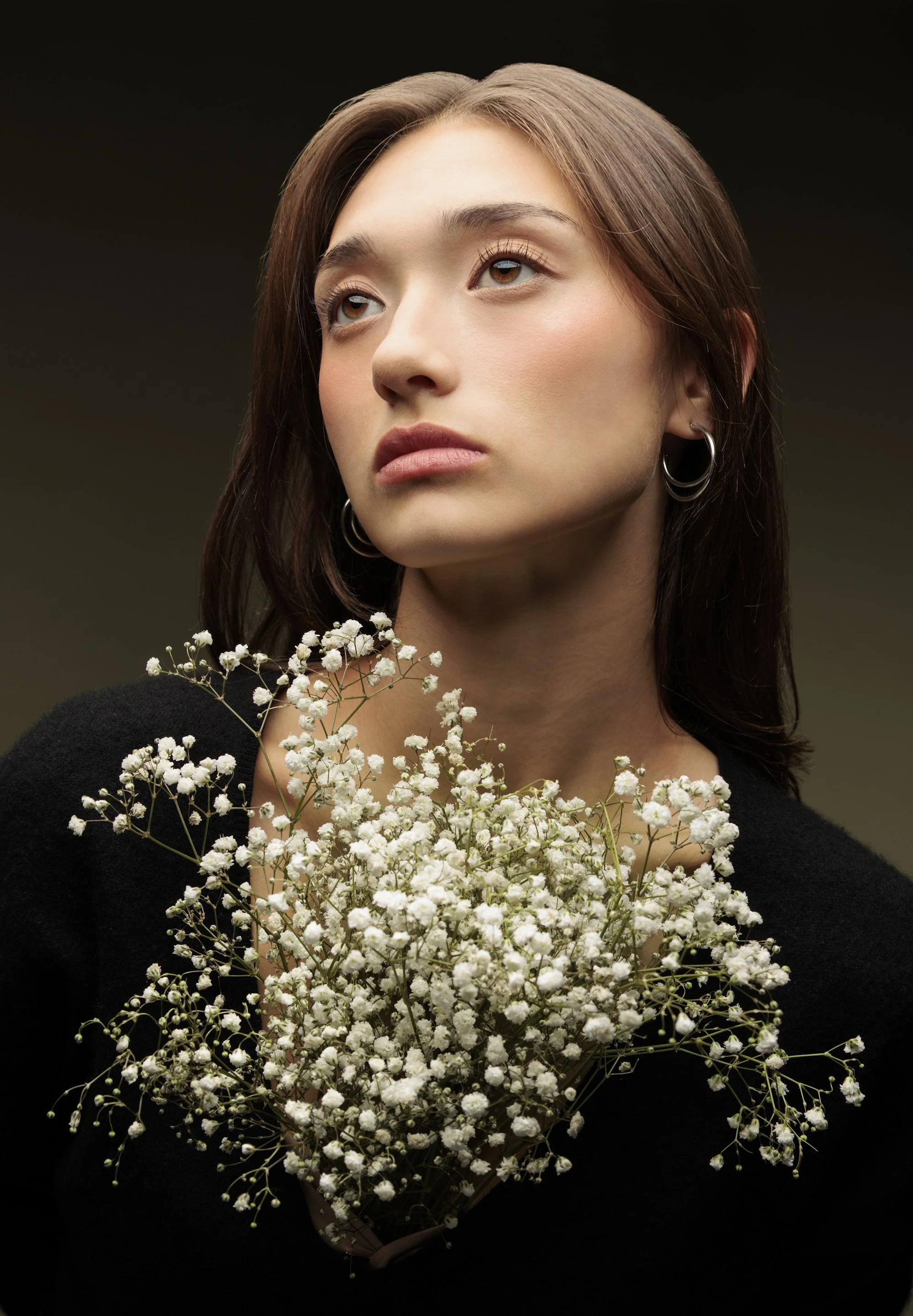 Soft pink makeup that enhances her eyes, paired with delicate baby's breath floral accents.