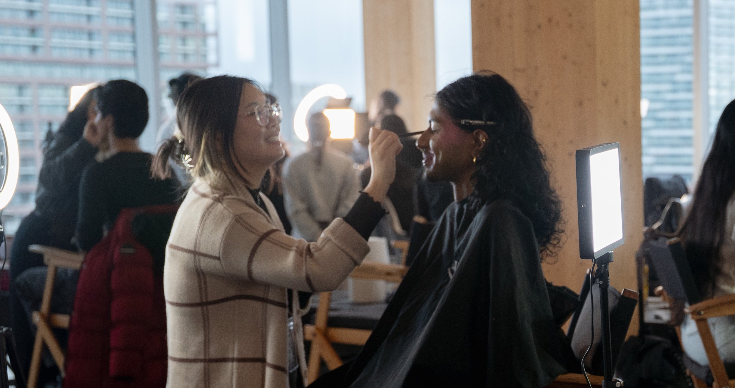 Makeup artist Alanna applying makeup to a model as they share a laugh.