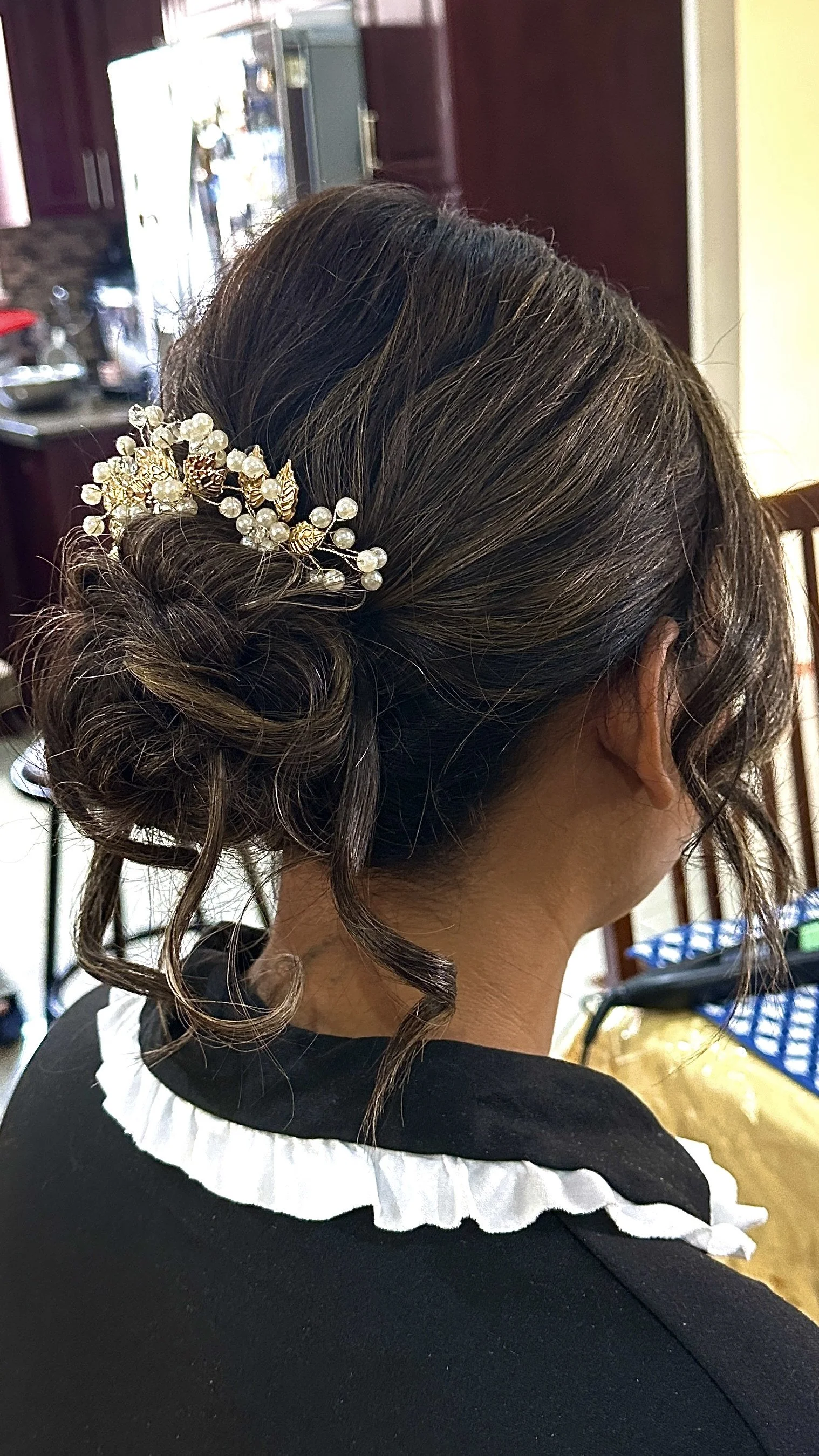 Bride wearing a delicate, soft low bridal bun with romantic face-framing tendrils.