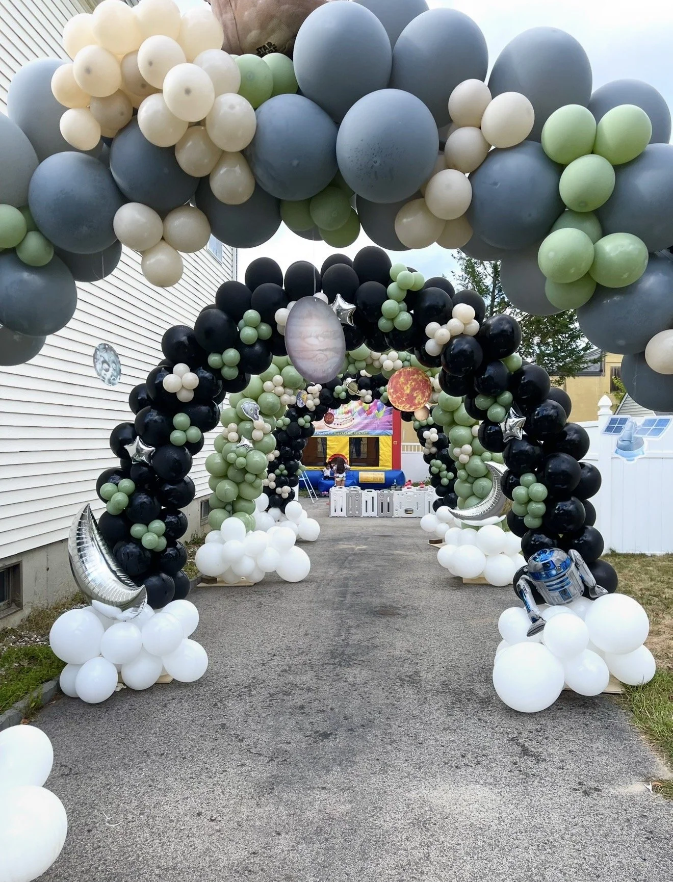 Colorful balloon arch with planets and space-themed decorations, set up in a backyard for a space-themed party or event.