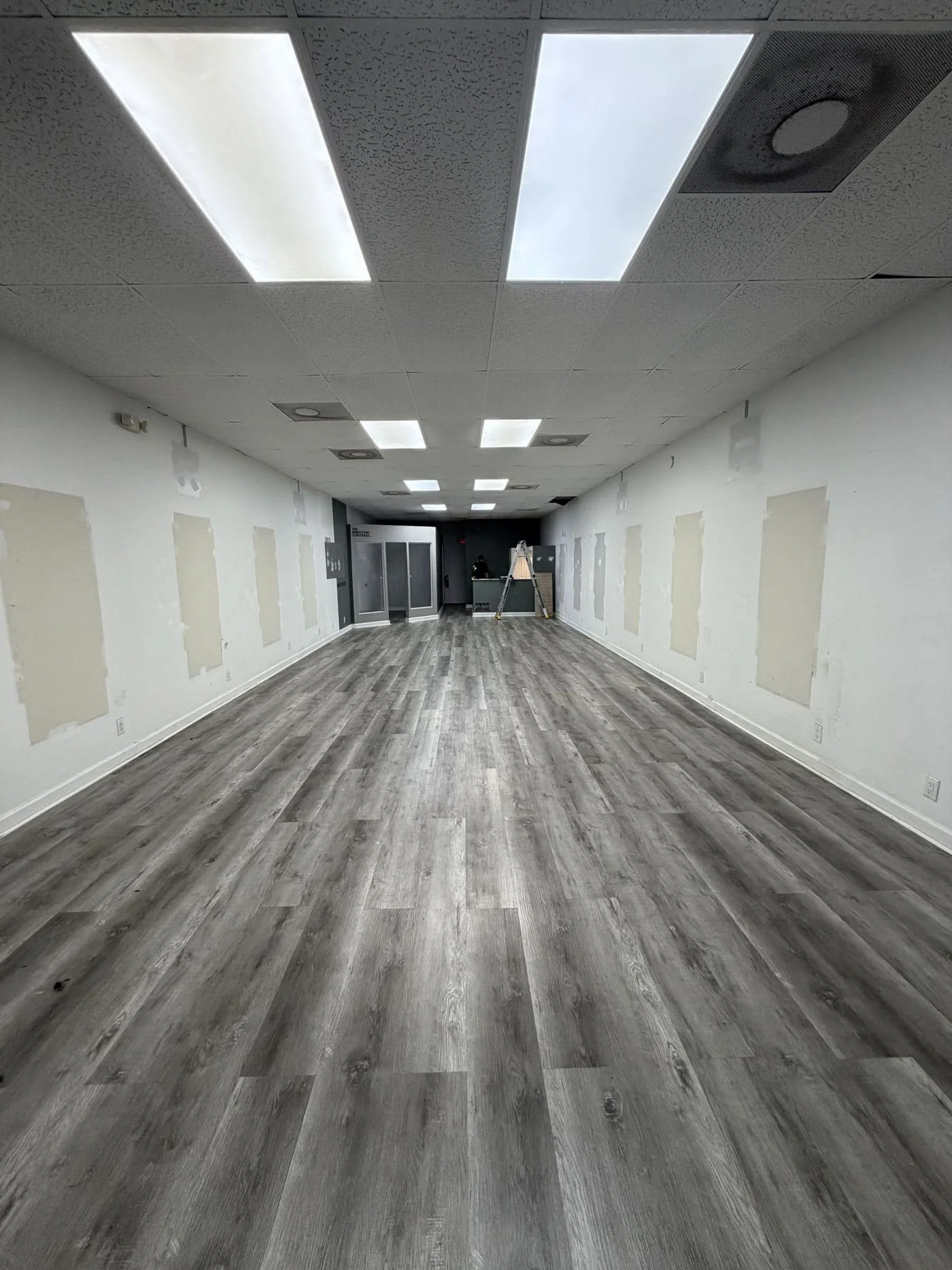 Barbershop space before: empty room with patched walls