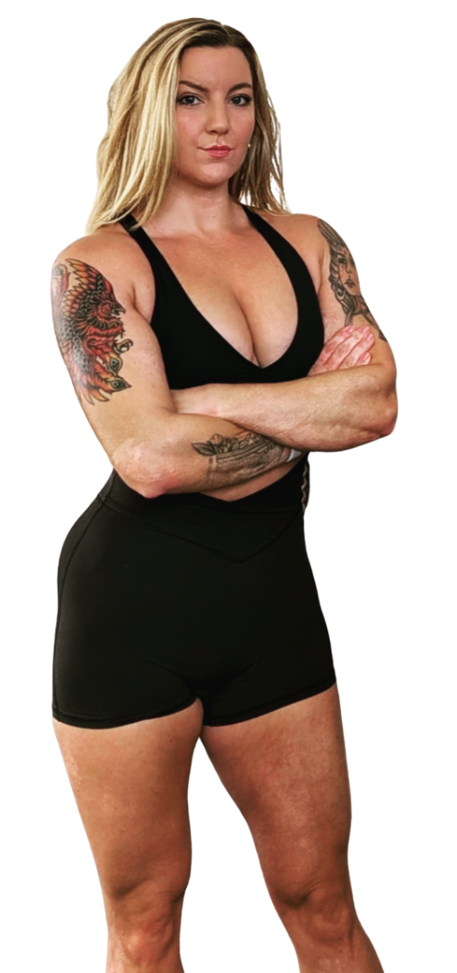 Rachel Huncke is a blonde woman with tattoos on her arms is standing with her arms crossed, wearing a black sports bra and black shorts.