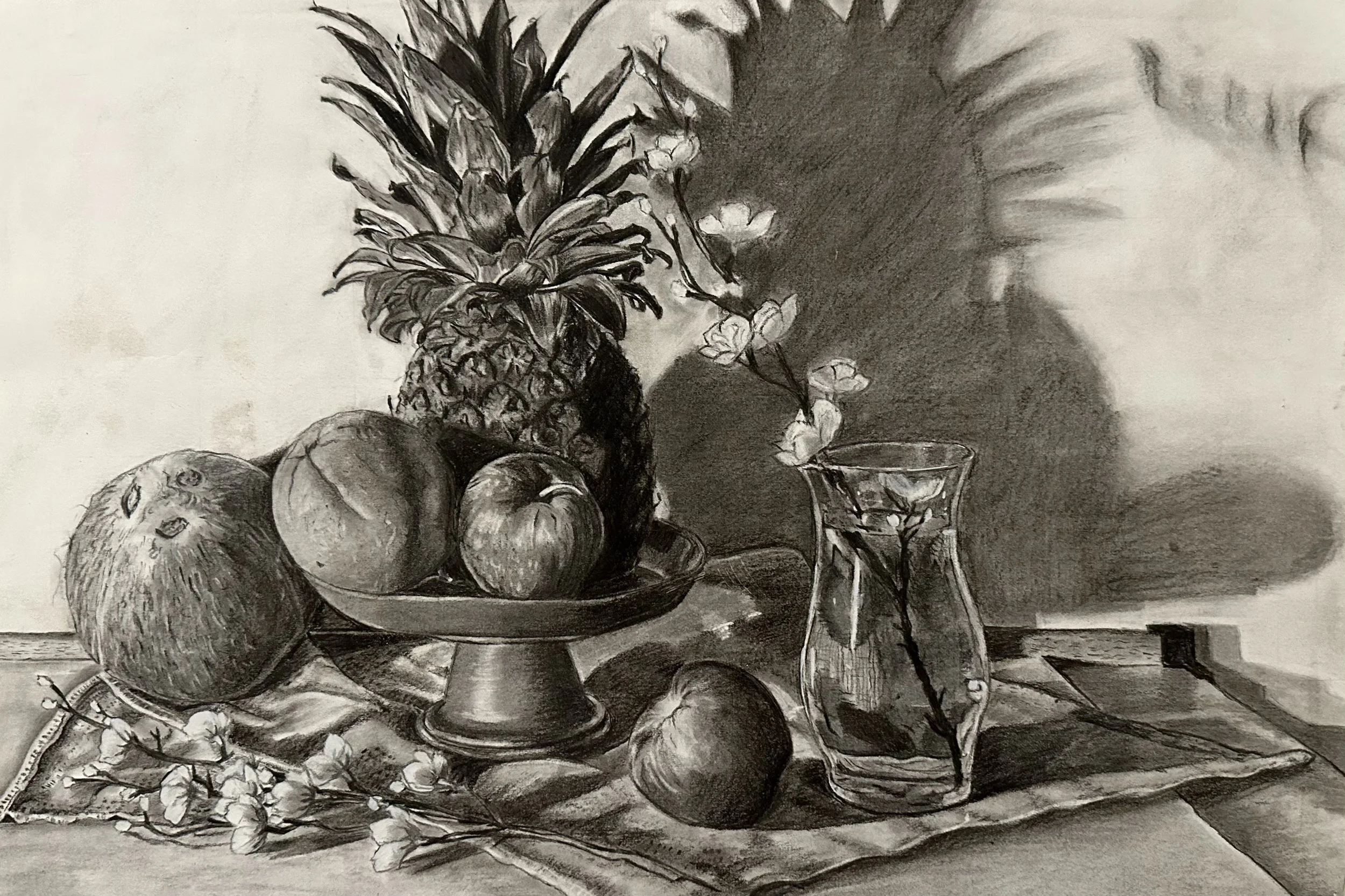 A black and white drawing of a still life composition, featuring a pineapple, an apple, a peach, and a coconut arranged on a table with a bowl and a glass. A draped cloth is in the background.