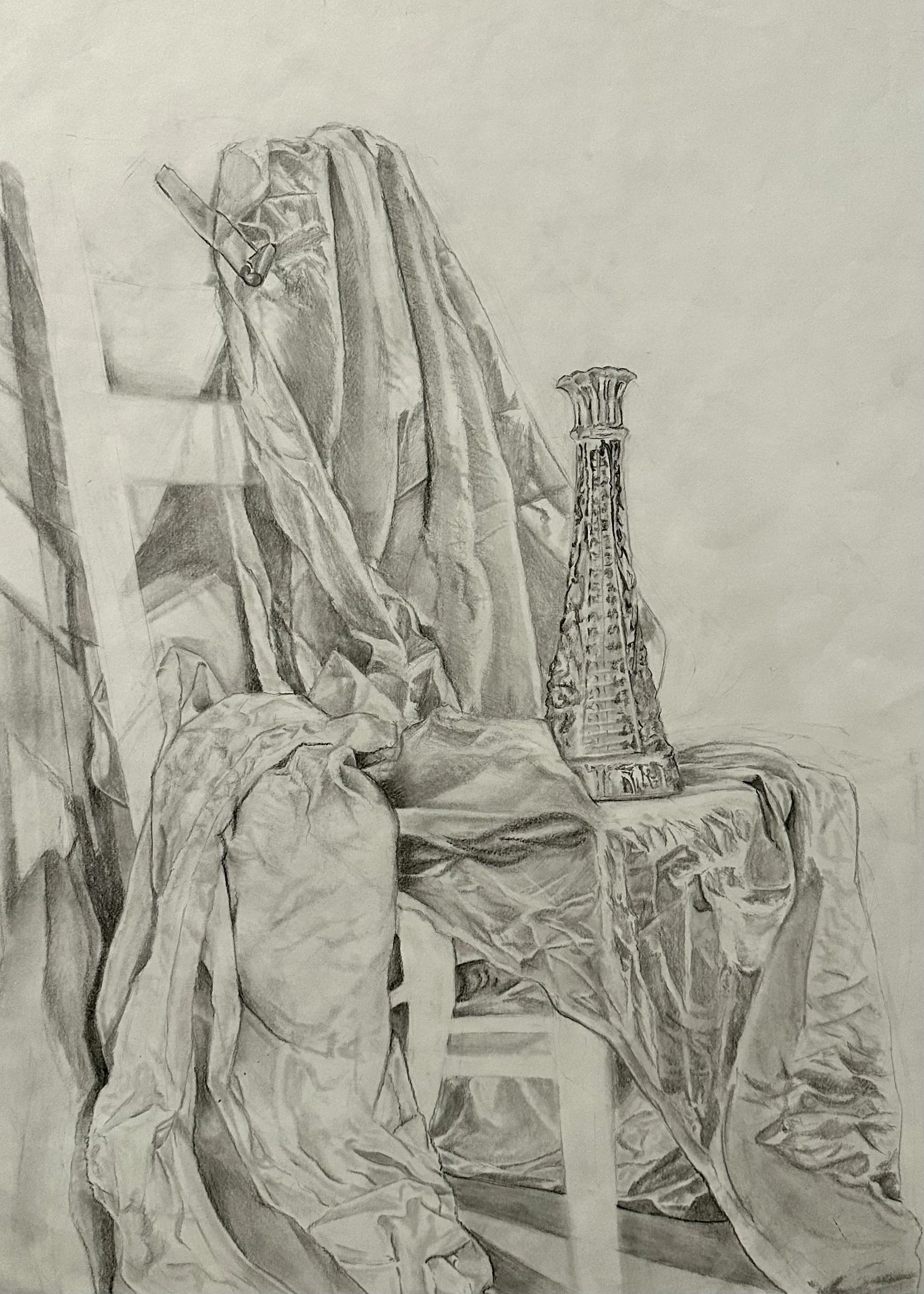 The black and white pencil drawing depicts a still-life composition, including a piece of fabric draped over a chair and a glass vase.