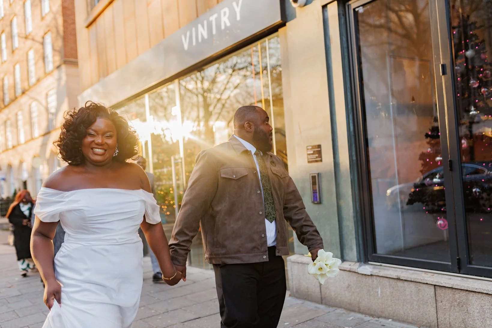 Newlywed couple holding hands while walking through central Bristol streets during their post-wedding portrait session.