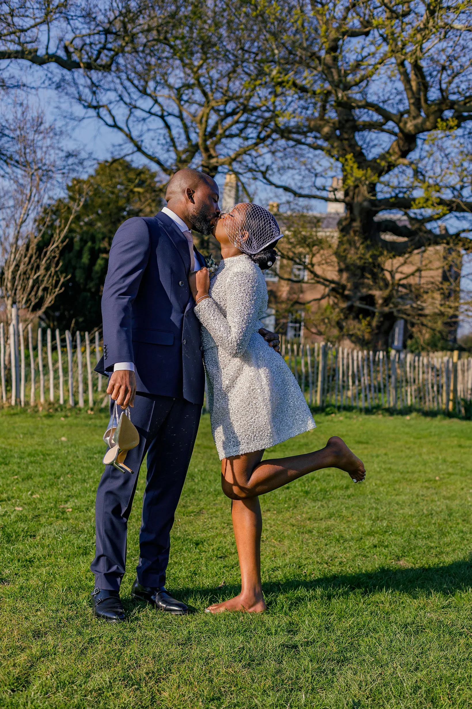 Newlywed couple sharing an intimate embrace while walking on the large lawn behind Merton Register Office in South West London.