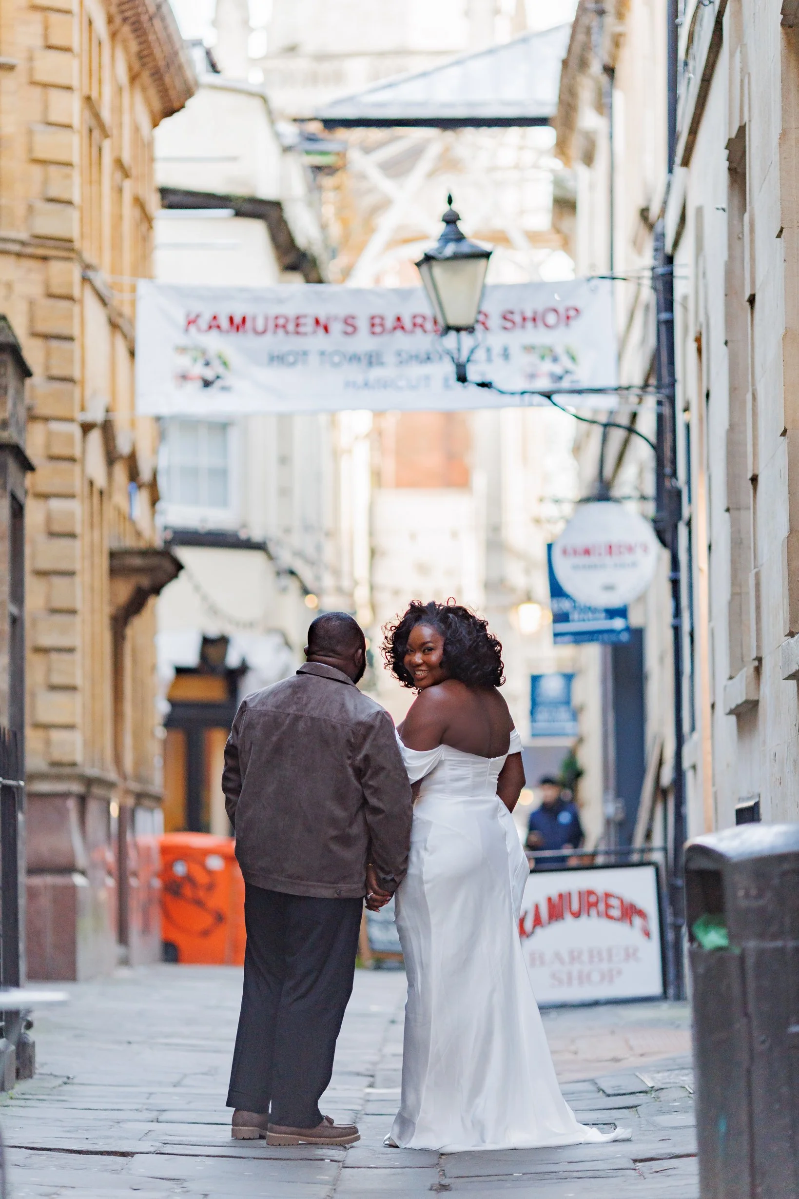 Newlywed couple holding hands while walking through central Bristol streets during their post-wedding portrait session.