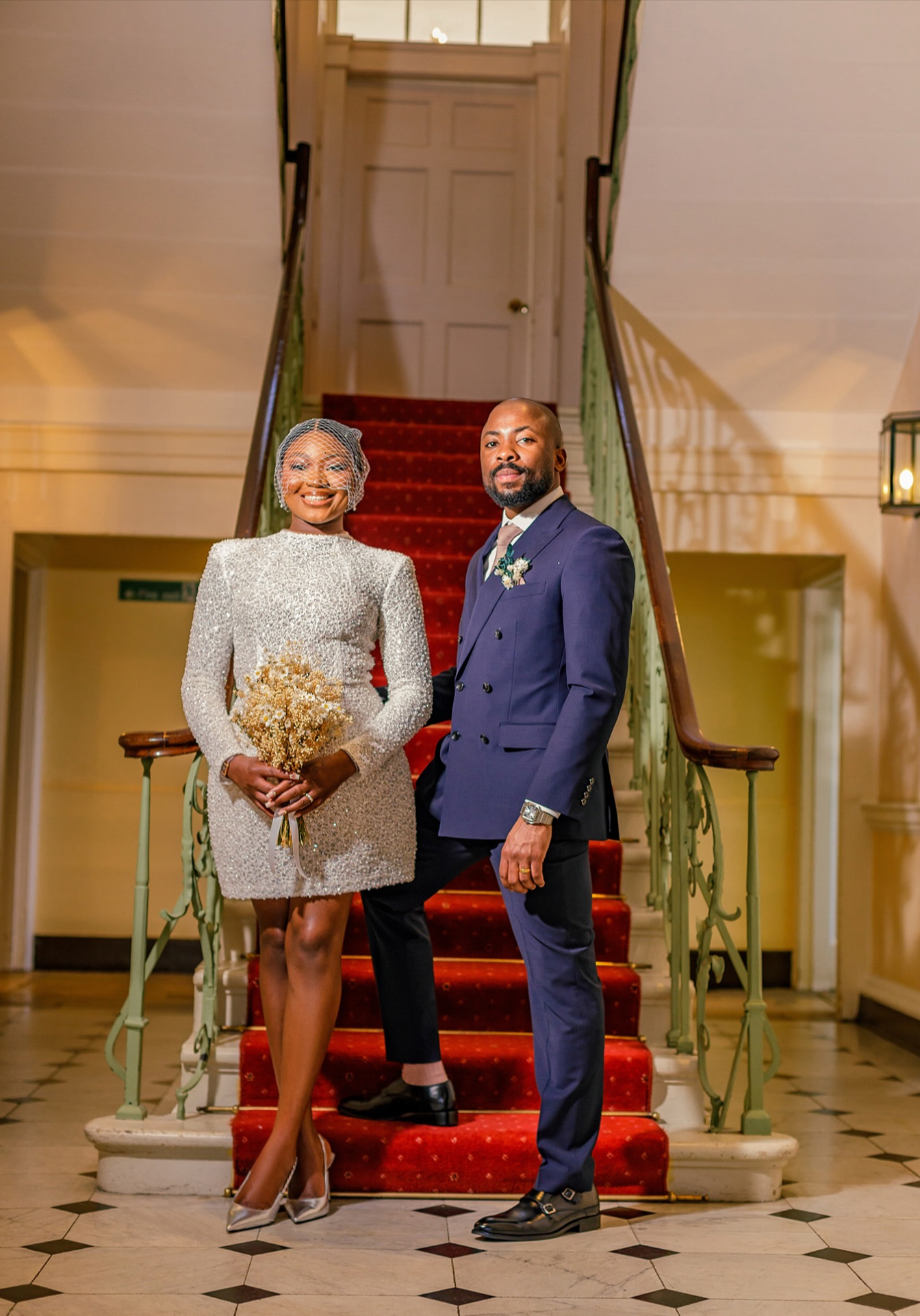 Newlywed couple standing under stained glass windows inside the dramatic Albert Hall during a Manchester wedding.