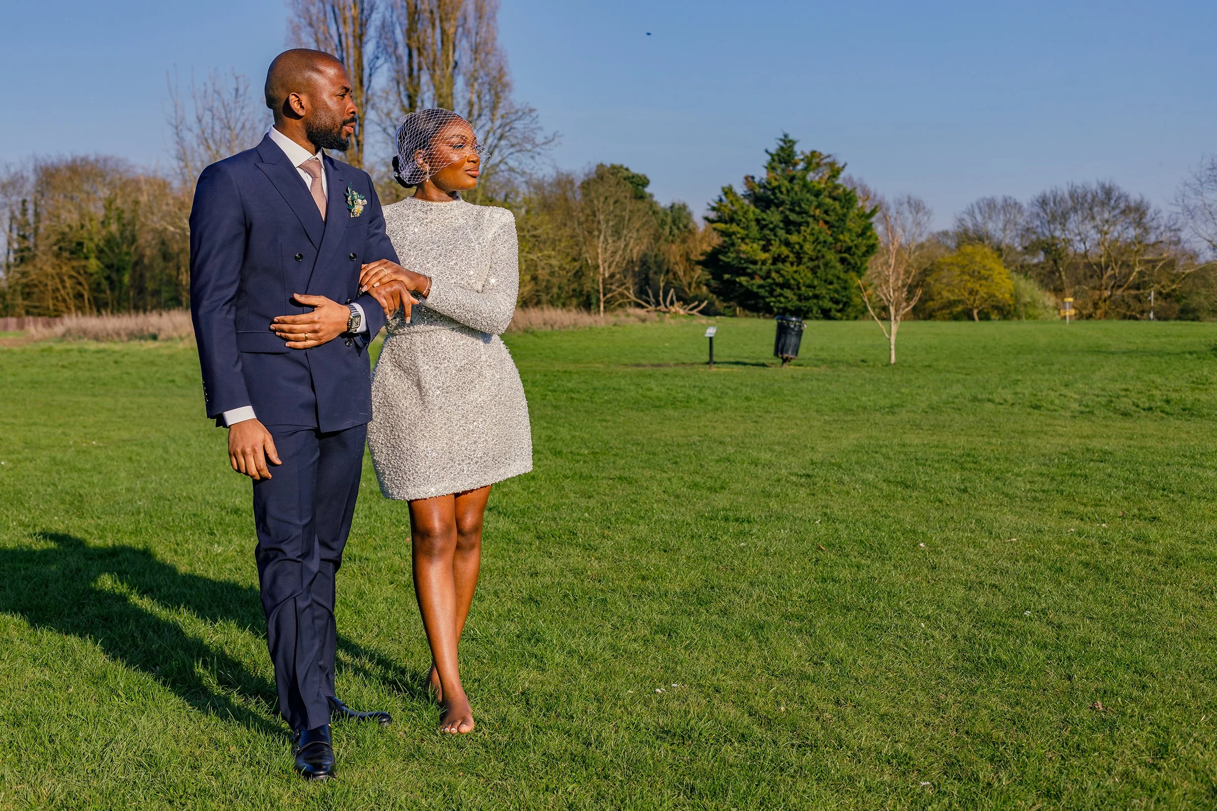 Newlywed couple sharing an intimate embrace while walking on the large lawn behind Merton Register Office in South West London.
