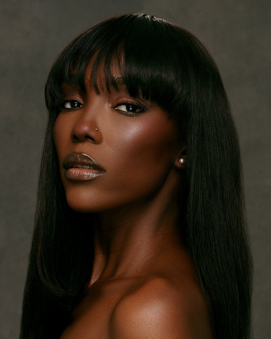 Model displaying natural skin texture and luminous glow during a high-key skincare campaign shoot in a London studio.