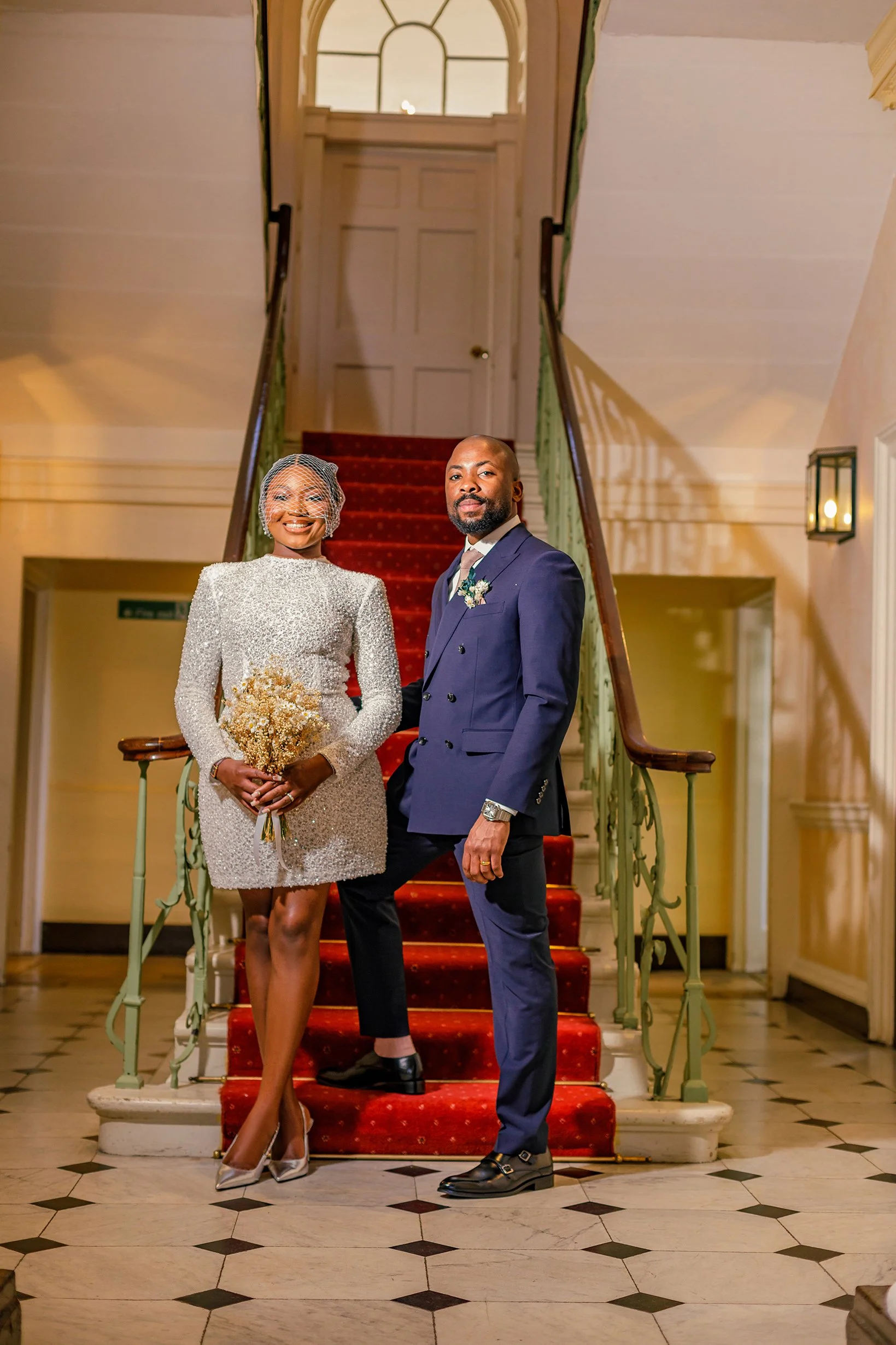 Newlyweds standing together on the classic interior staircase inside Merton Register Office.