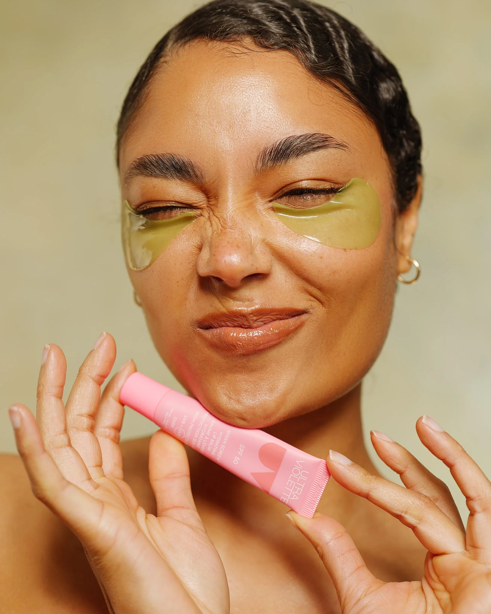 Model displaying natural skin texture and luminous glow during a high-key skincare campaign shoot in a London studio.