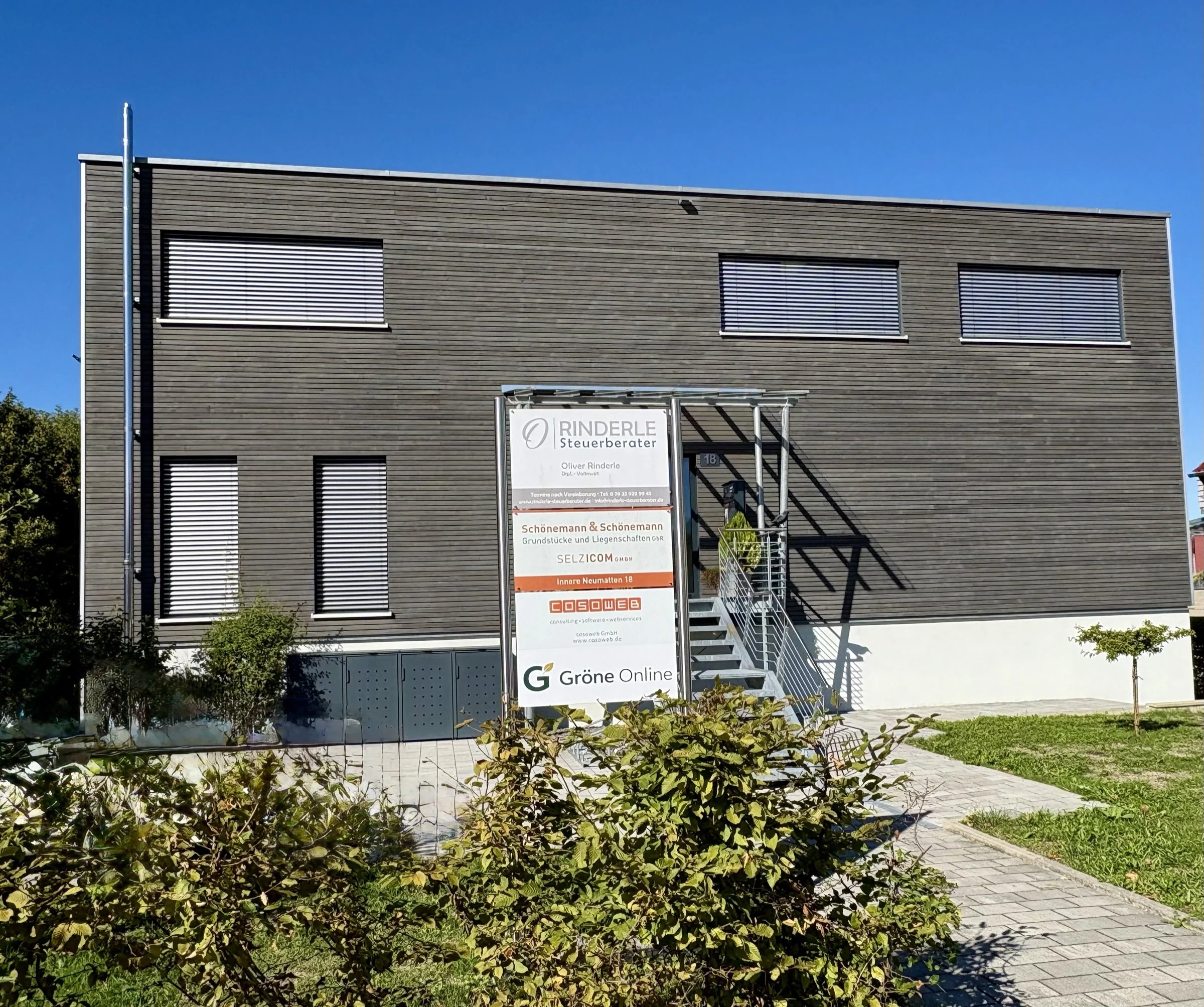 Außenansicht der Kanzlei Rinderle Steuerberater in Staufen mit dunkler Holzfassade und Firmenschild