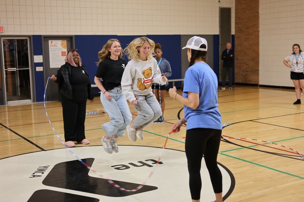 Two trainees jumping a long rope together, mid-air and smiling