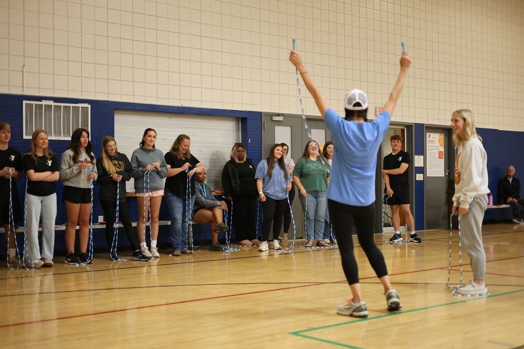 The founder, arms raised with a jump rope, leading a line of trainees