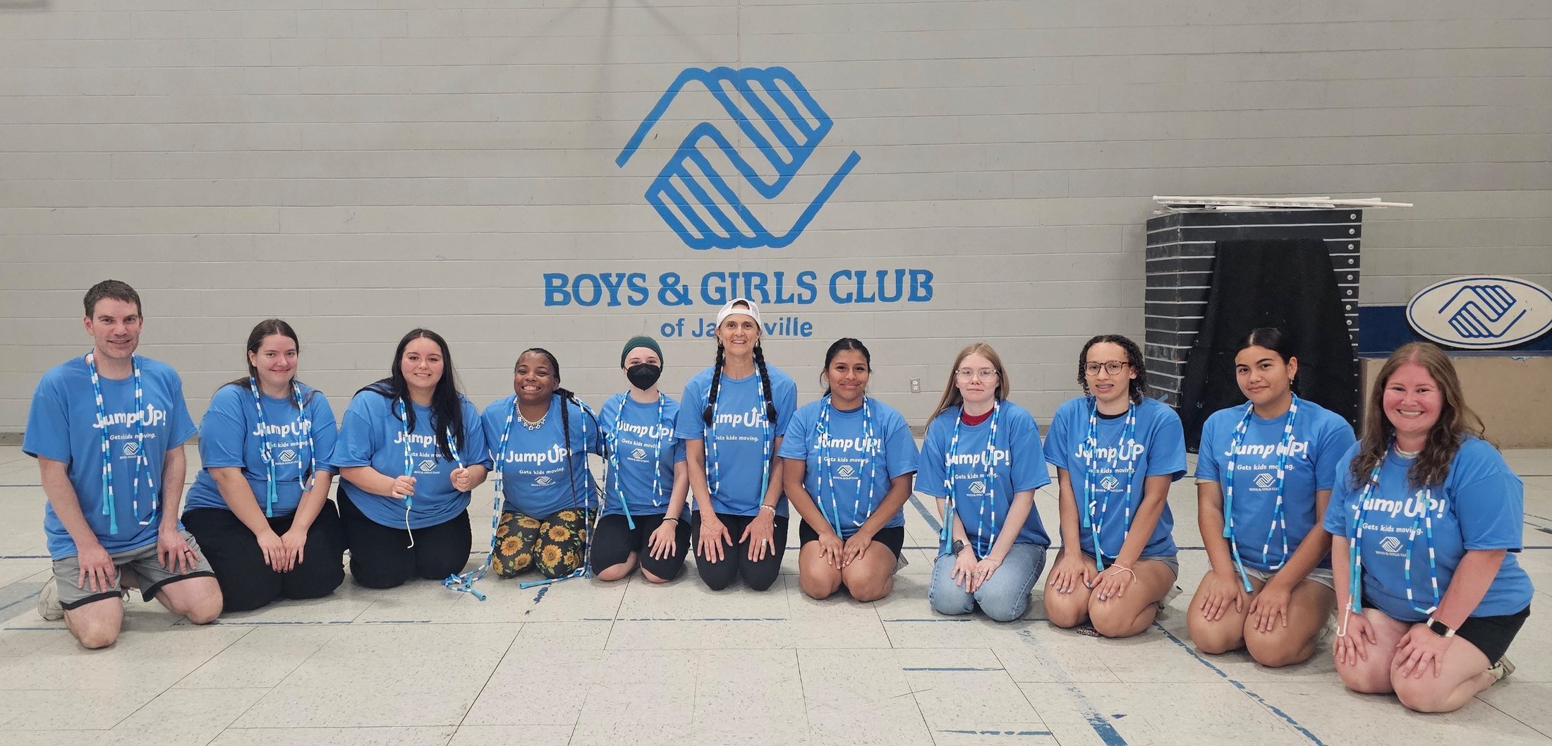 Boys & Girls Club of Janesville staff and teen leaders in Jump UP! t-shirts with beaded jump ropes, in front of the club logo