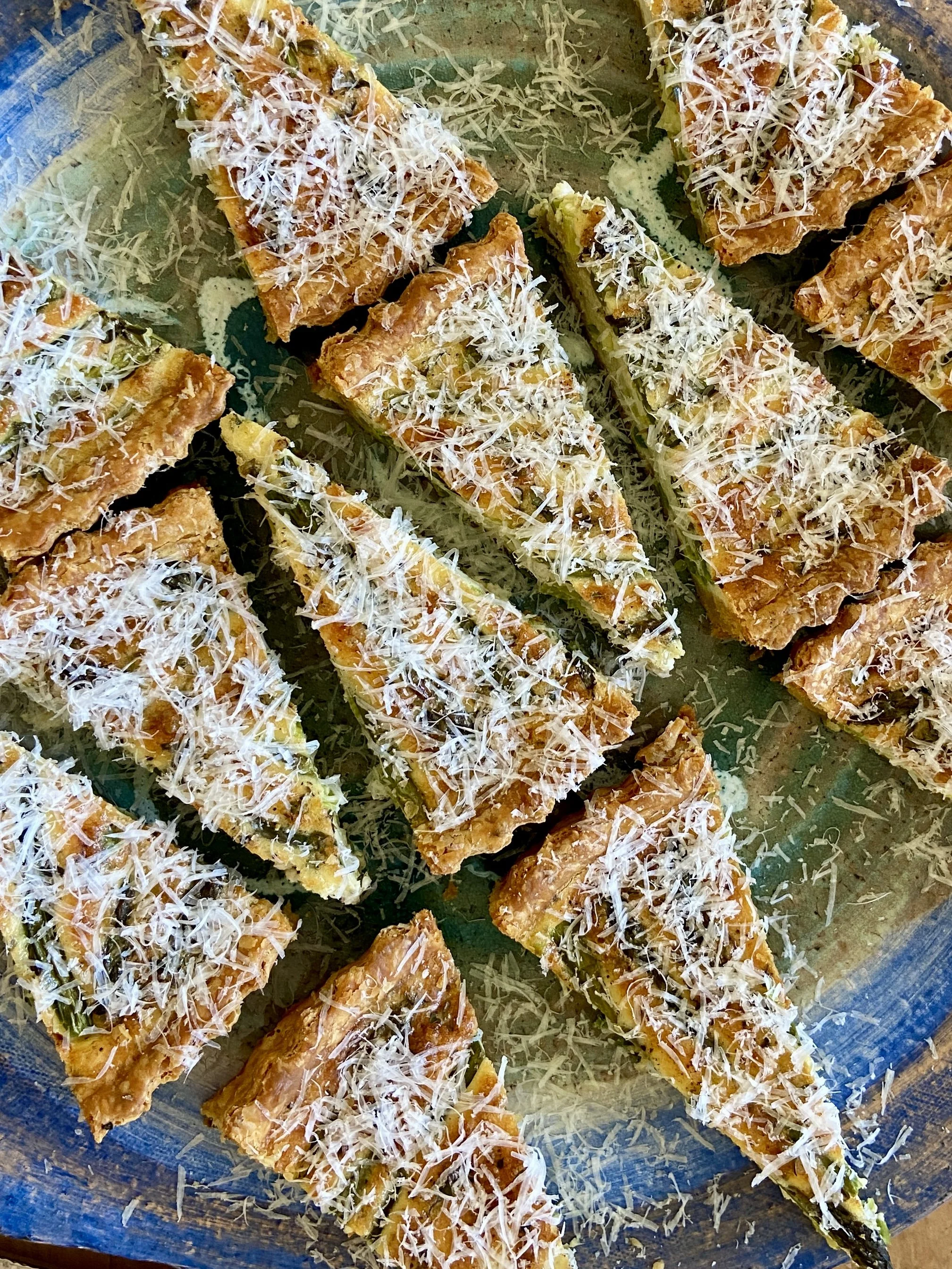 Close-up image of grilled fish fillets topped with shredded cheese on a blue platter.