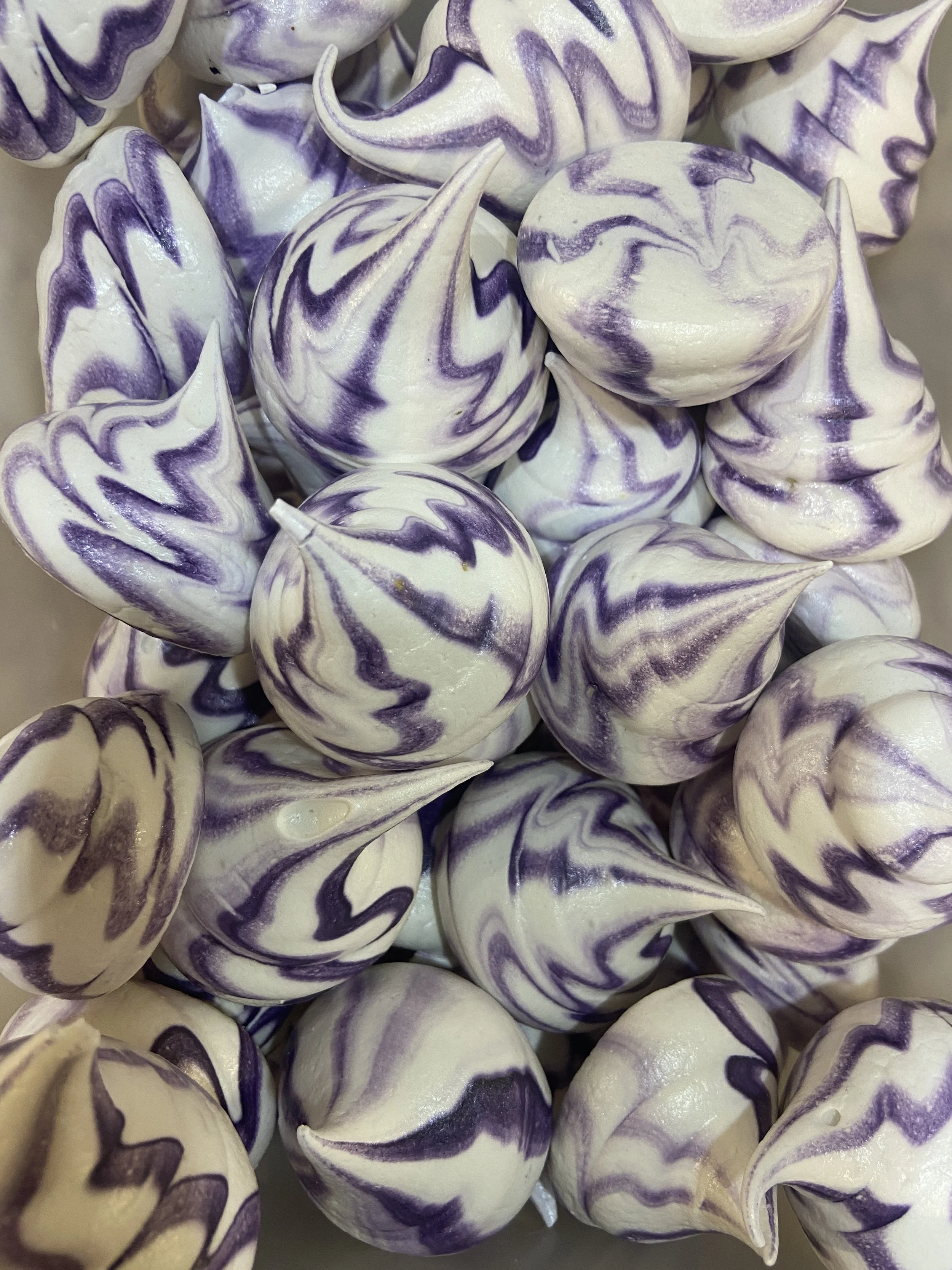 Close-up of swirled purple and white meringue cookies with pointed tips.
