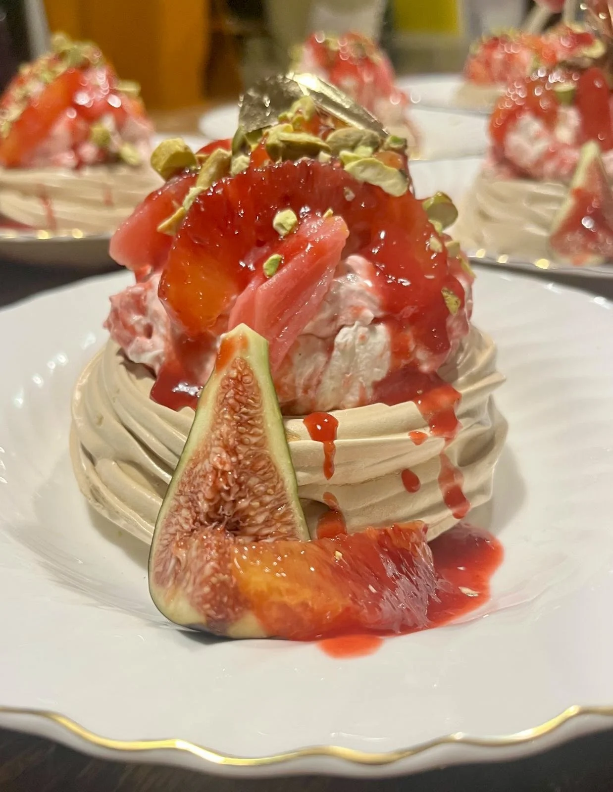 Dessert topped with fresh strawberries, figs, chopped nuts, and a drizzle of syrup, served on a white plate.