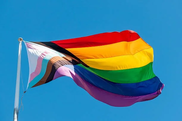 Rainbow pride flag flying against a clear blue sky.