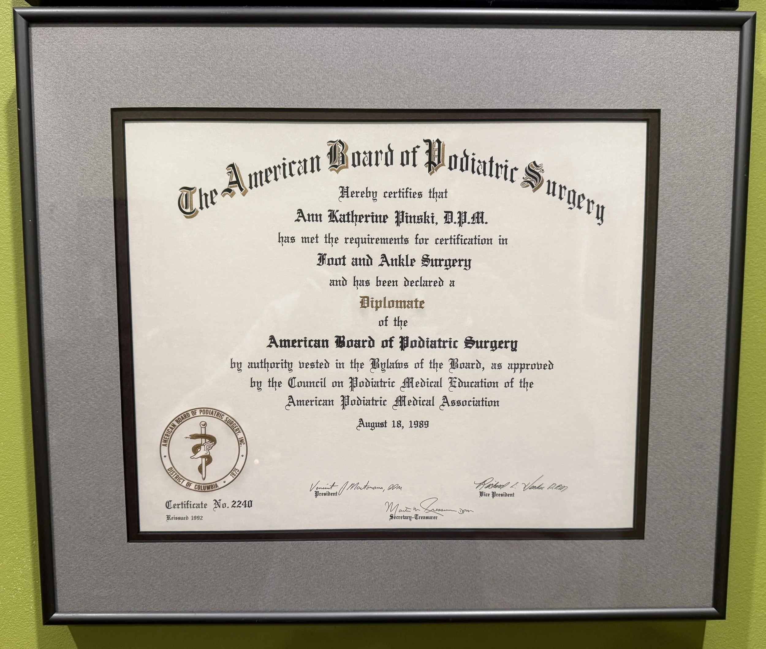 A framed certificate from the American Board of Podiatric Surgery awarded to Ann Katherine Pinski, D.P.M., dated August 18, 1999, with signatures at the bottom.