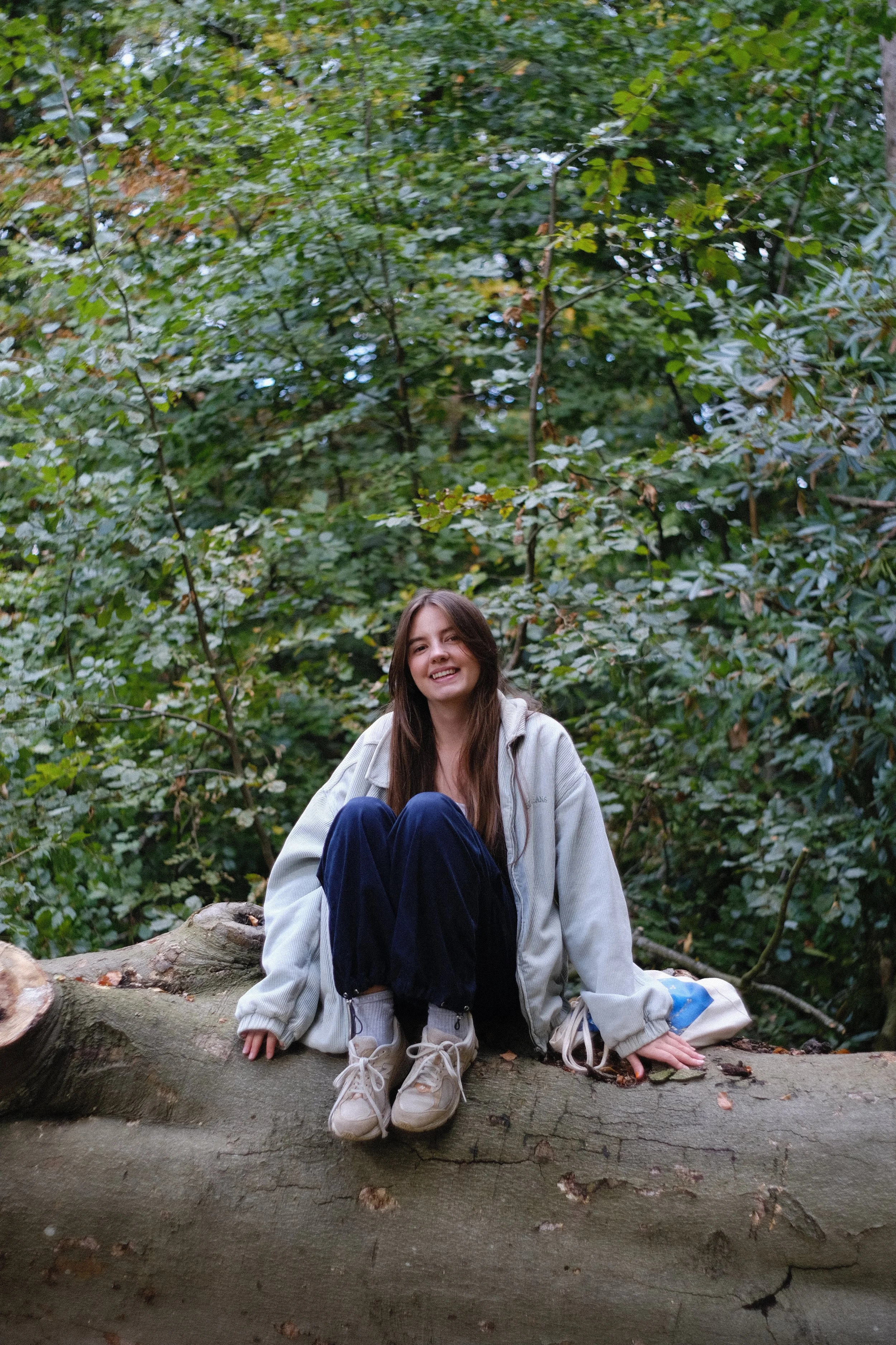 A young illustrator, sat on a tree surrounded by nature.