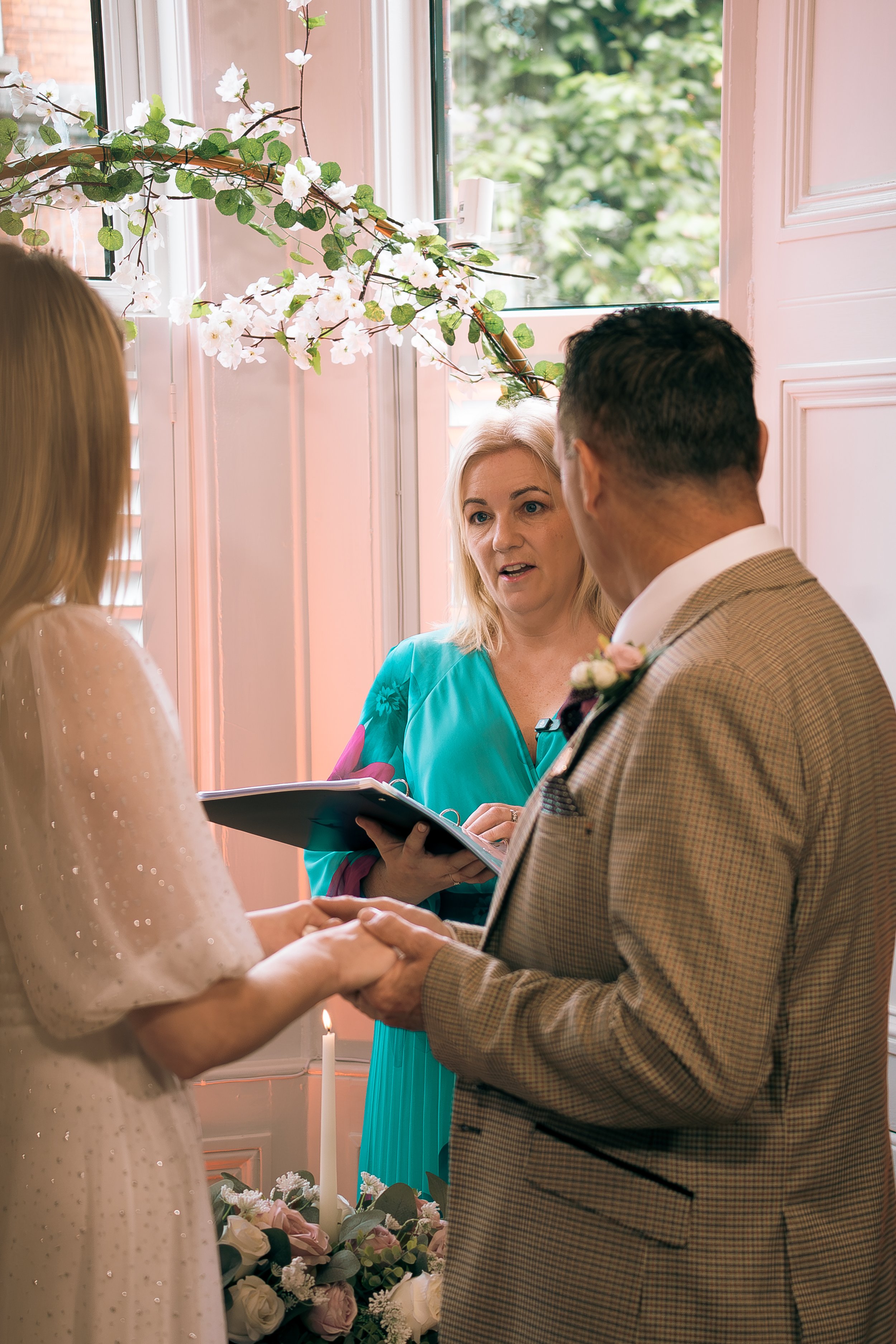 A wedding ceremony with a bride and groom holding hands and exchanging vows, with Karen O'Beirne Registered Solemniser & Wedding Celebrant