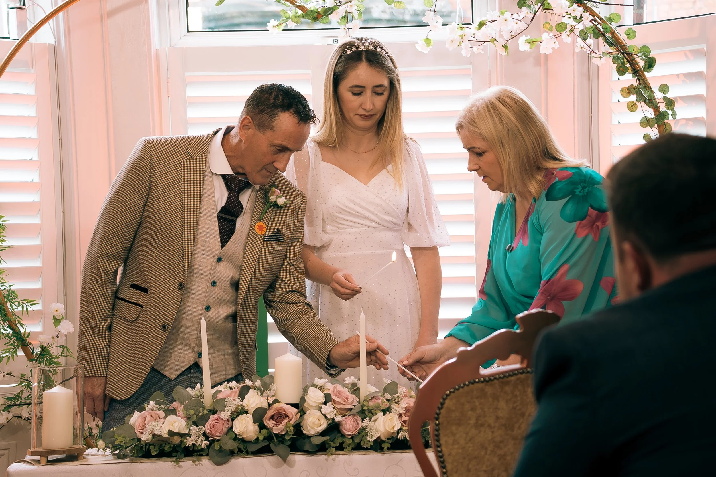 A bride and groom lighting their unity candles during their wedding ceremony with Karen O'Beirne assisting them
