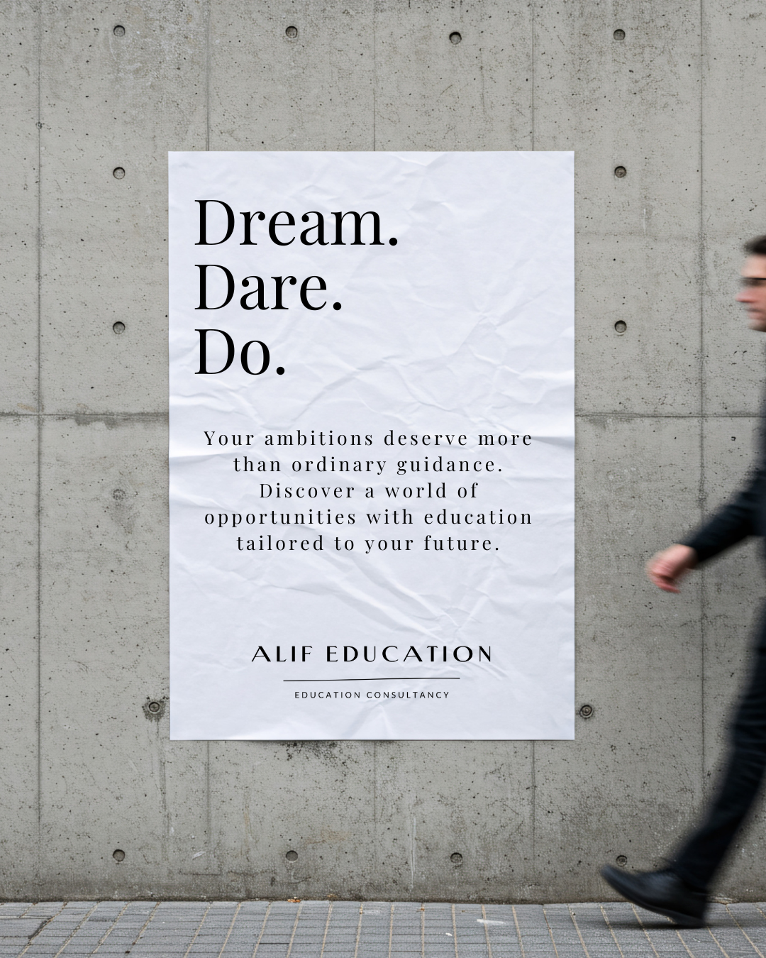 A large white poster with motivational text hangs on a gray concrete wall. The poster says, 'Dream. Dare. Do.' and promotes education opportunities by Alif Education.