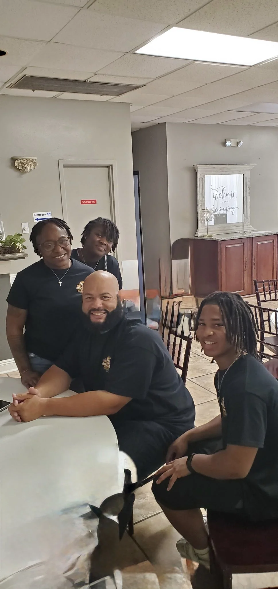 Four people smiling at a table in a restaurant, with a small dog near their feet.