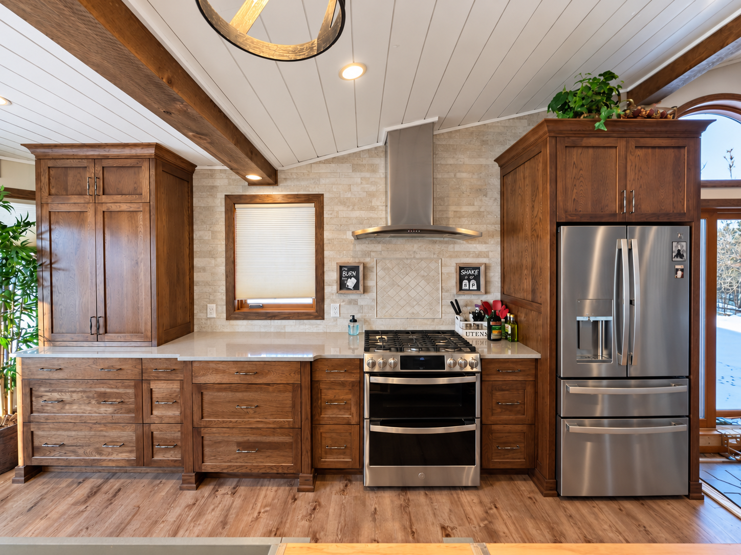 Kitchen with wooden cabinets, stainless steel appliances, a window with blinds, and a beige tile backsplash.