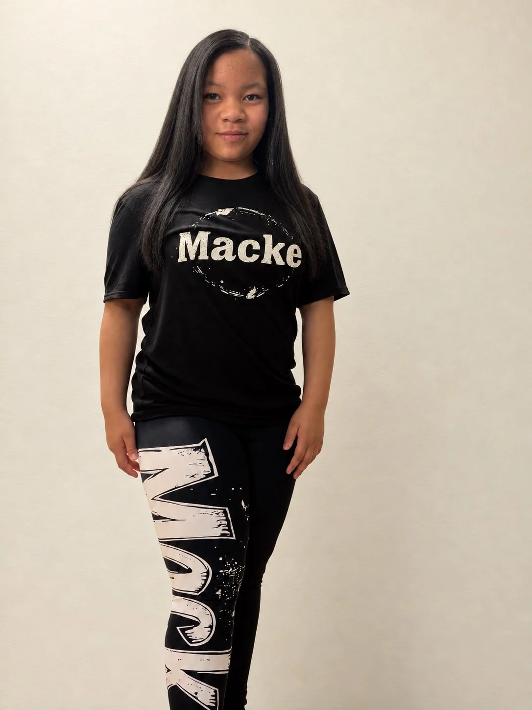 Model wearing a black Macke T-shirt and Macke graphic leggings.