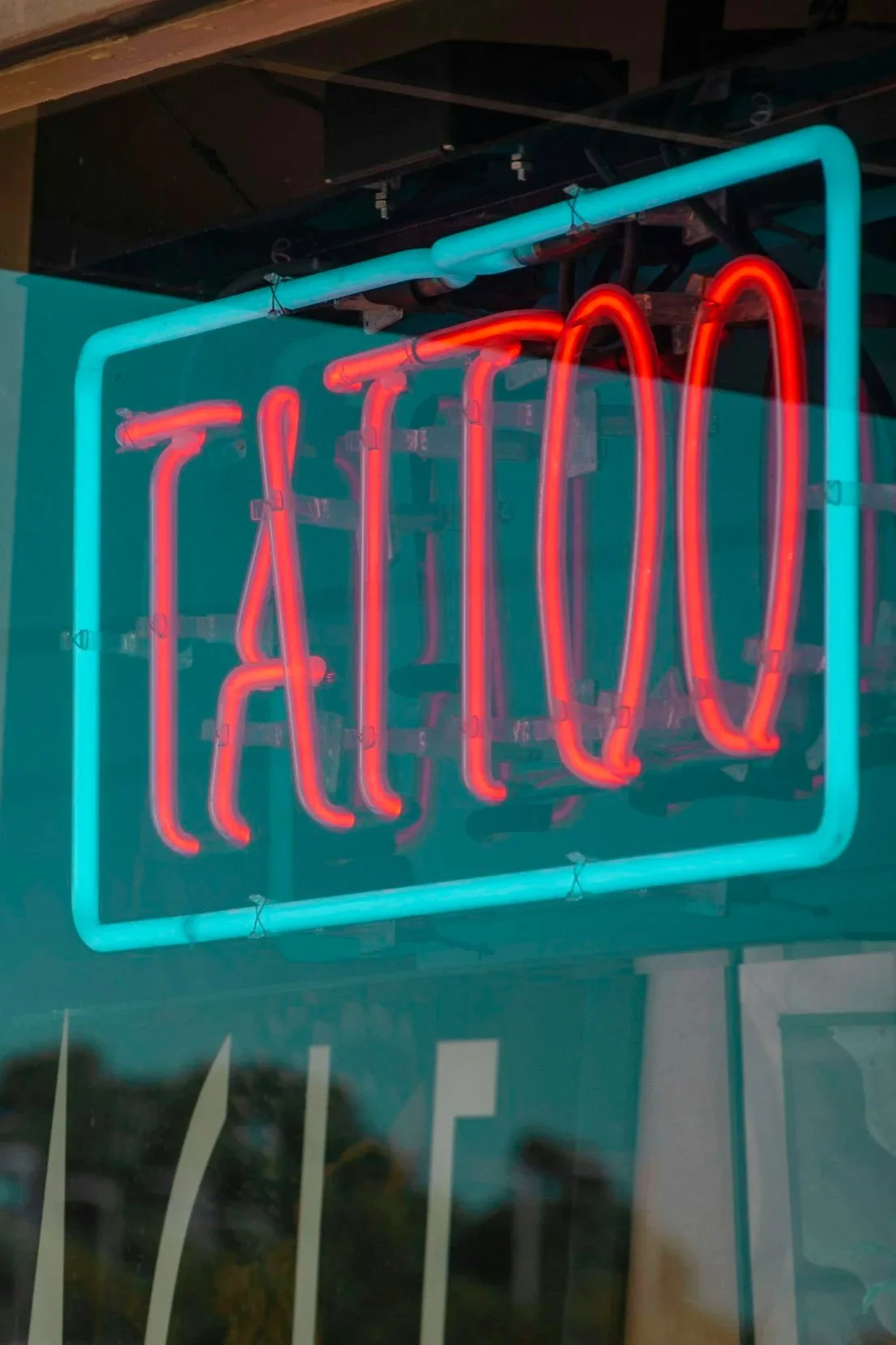 Tattoo shop window with a blue neon sign reading "Tattoo" in red