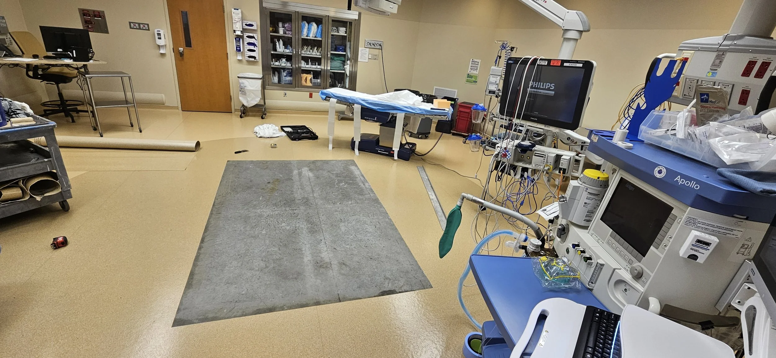 Empty hospital operating room with medical equipment, monitors, and surgical tables, appearing to be prepared for surgery.