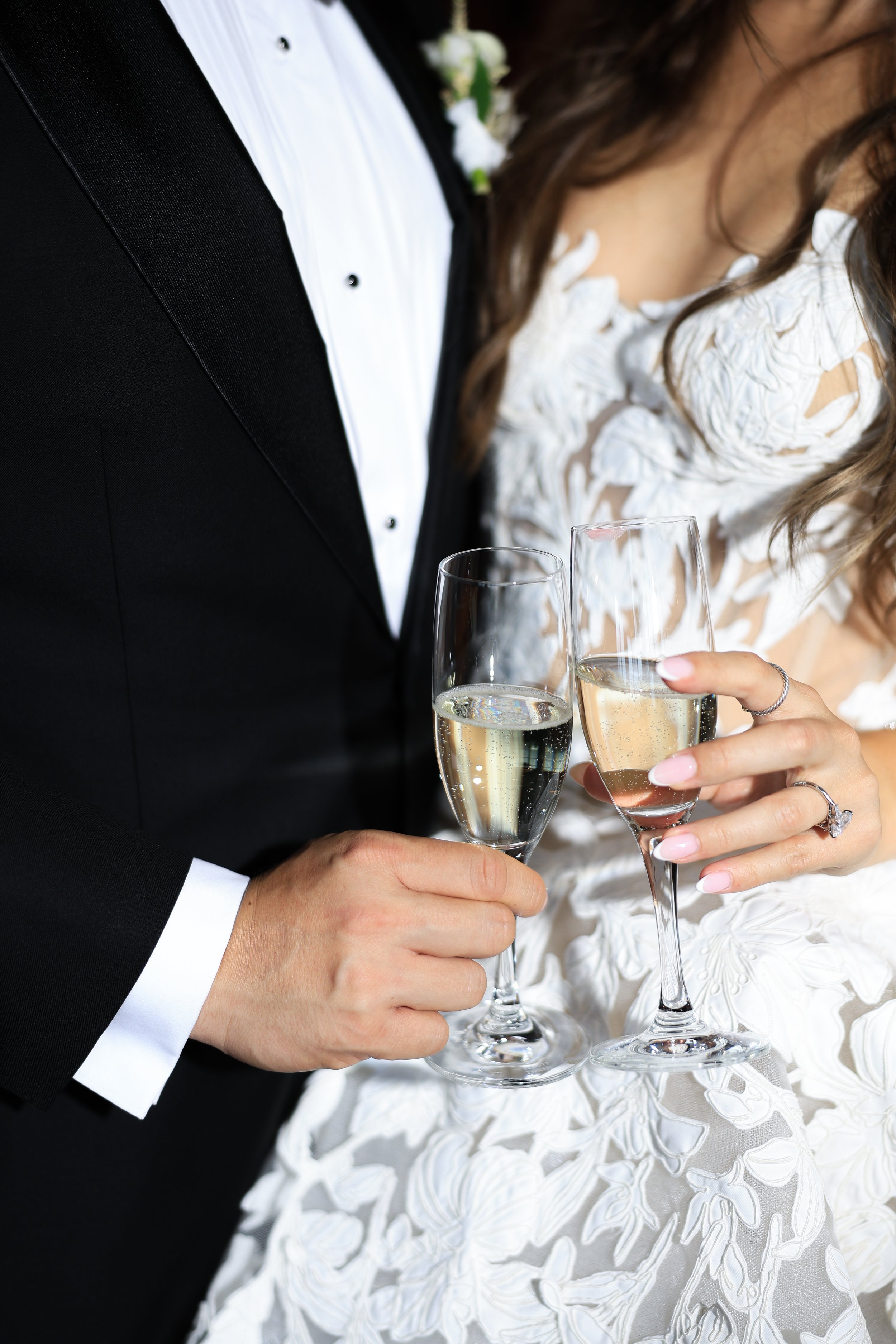 Close-up of a couple holding champagne glasses, dressed formally at a celebration.