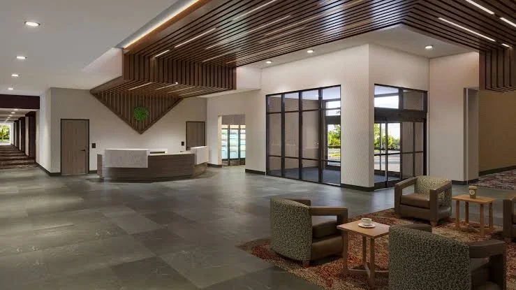 Modern hotel lobby with reception desk, wood slatted ceiling, glass doors, and lounge seating