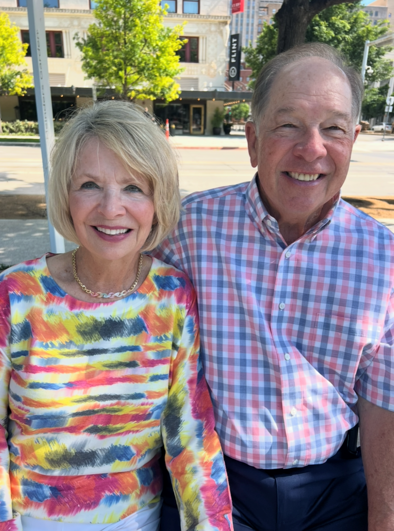 Smiling older couple posing together outdoors on a sunny city street