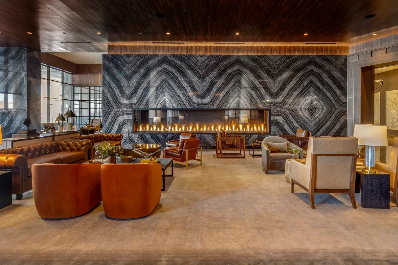 Luxury hotel lounge with leather seating, a long modern fireplace, and dramatic black-and-white marble wall