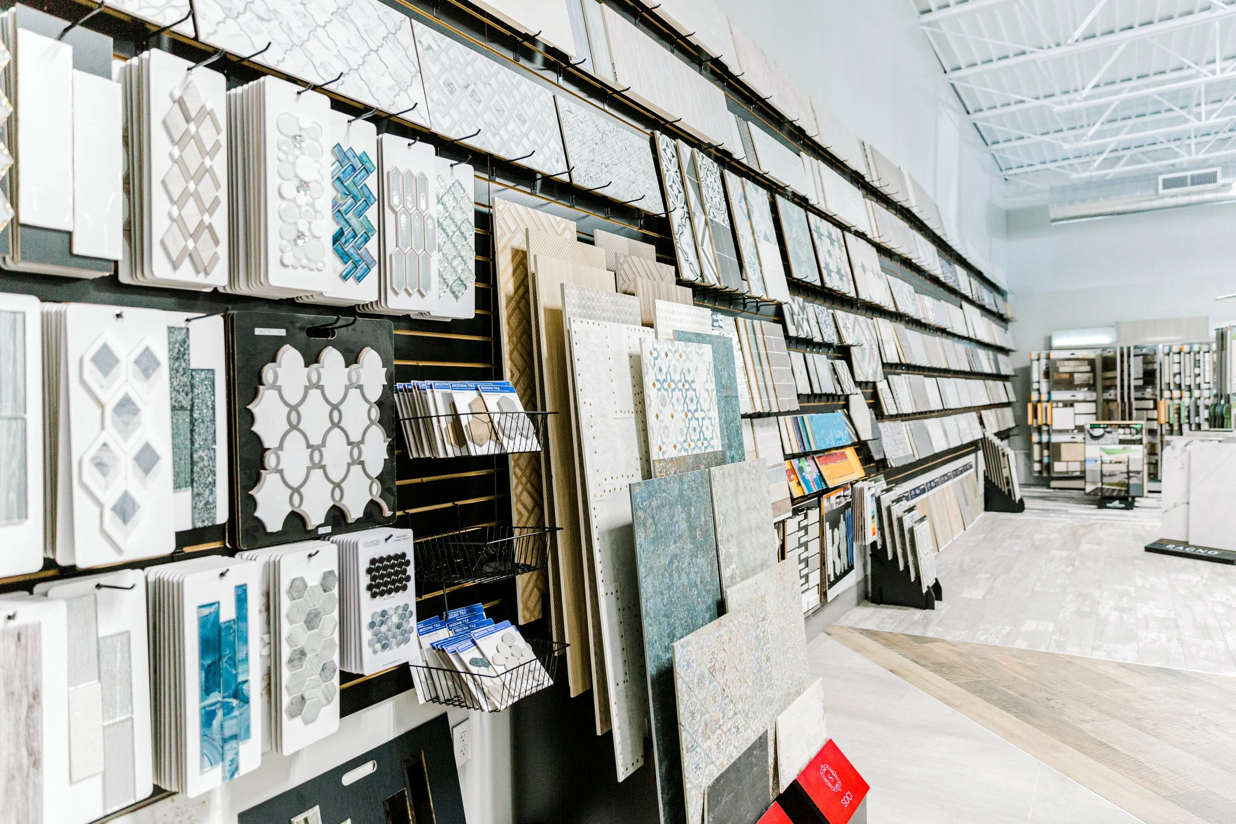 Tile showroom displaying wall-mounted ceramic tile samples, mosaic designs, and large flooring slabs