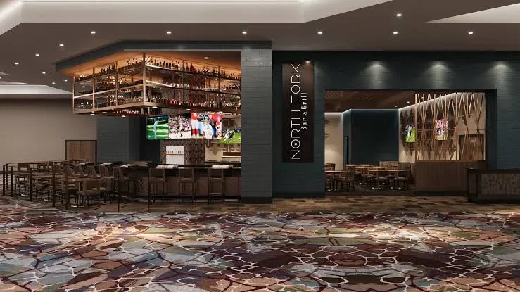 Modern North Fork Bar & Grill restaurant interior with a central bar, liquor shelves, dining tables, and patterned carpet.