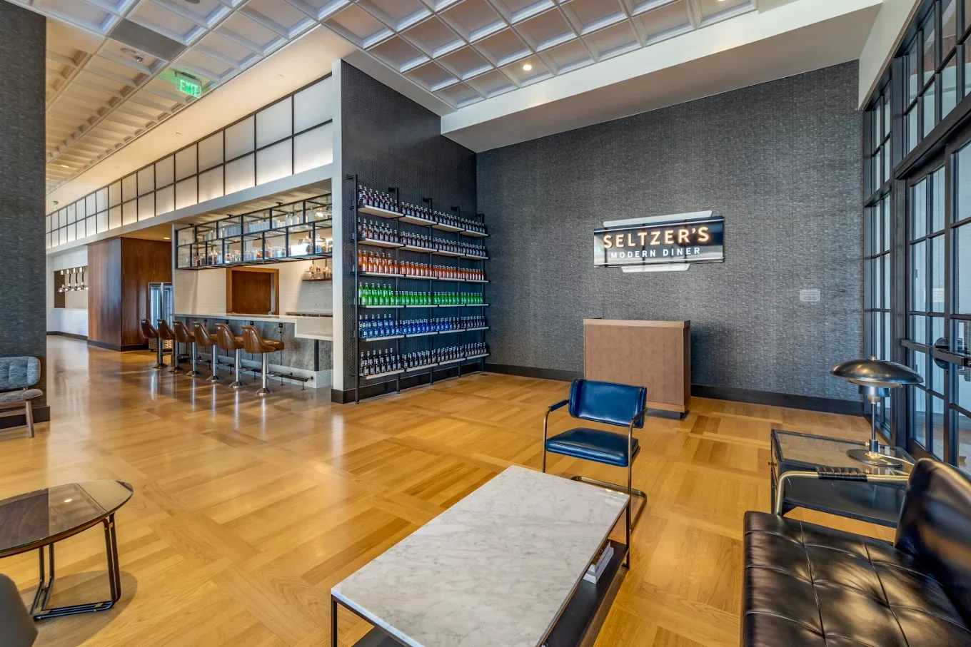 Interior of Seltzer’s Modern Diner with a bar, colorful bottle display, lounge seating, and wood parquet flooring.