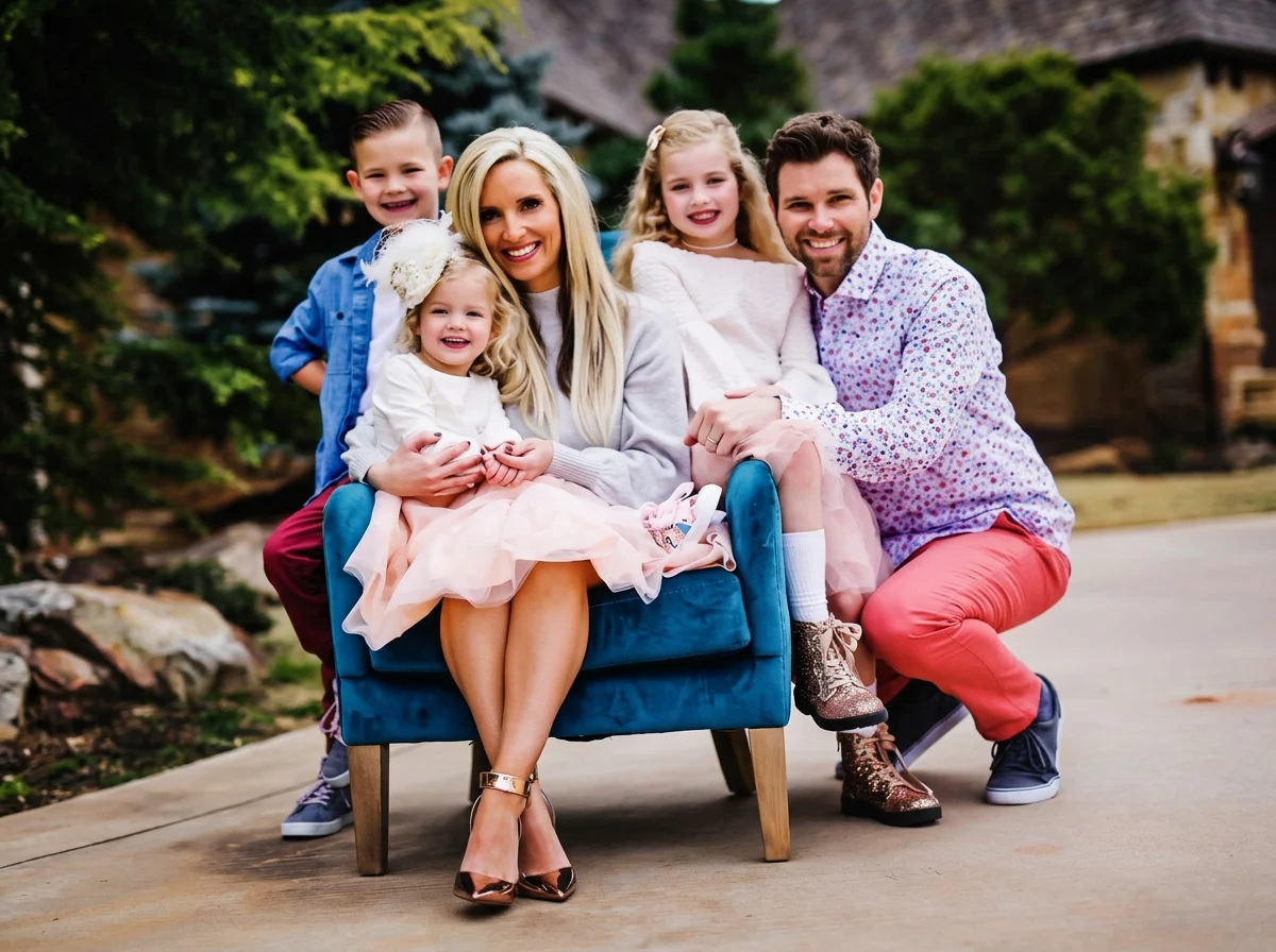 Smiling family of five posing outdoors around a blue armchair