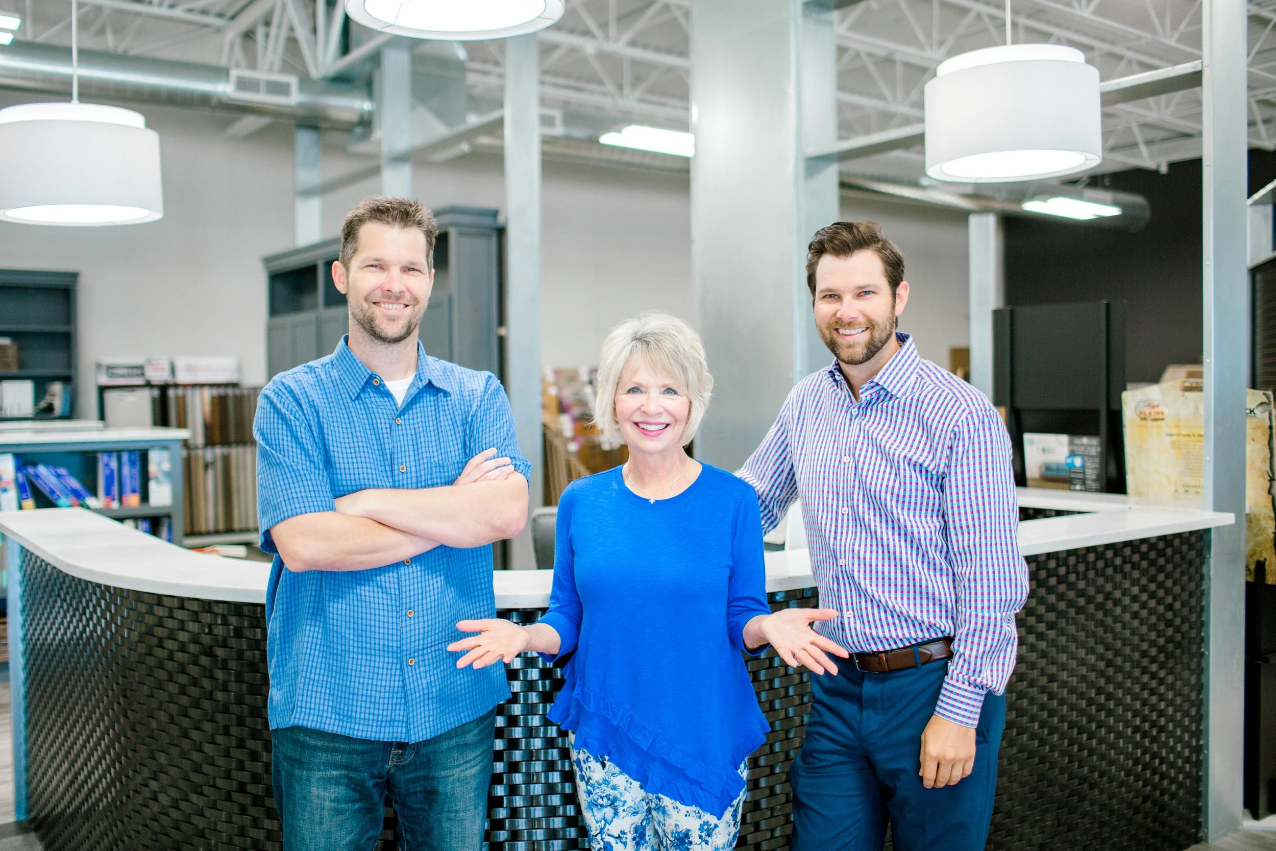 Three smiling people posing inside a modern retail store or showroom