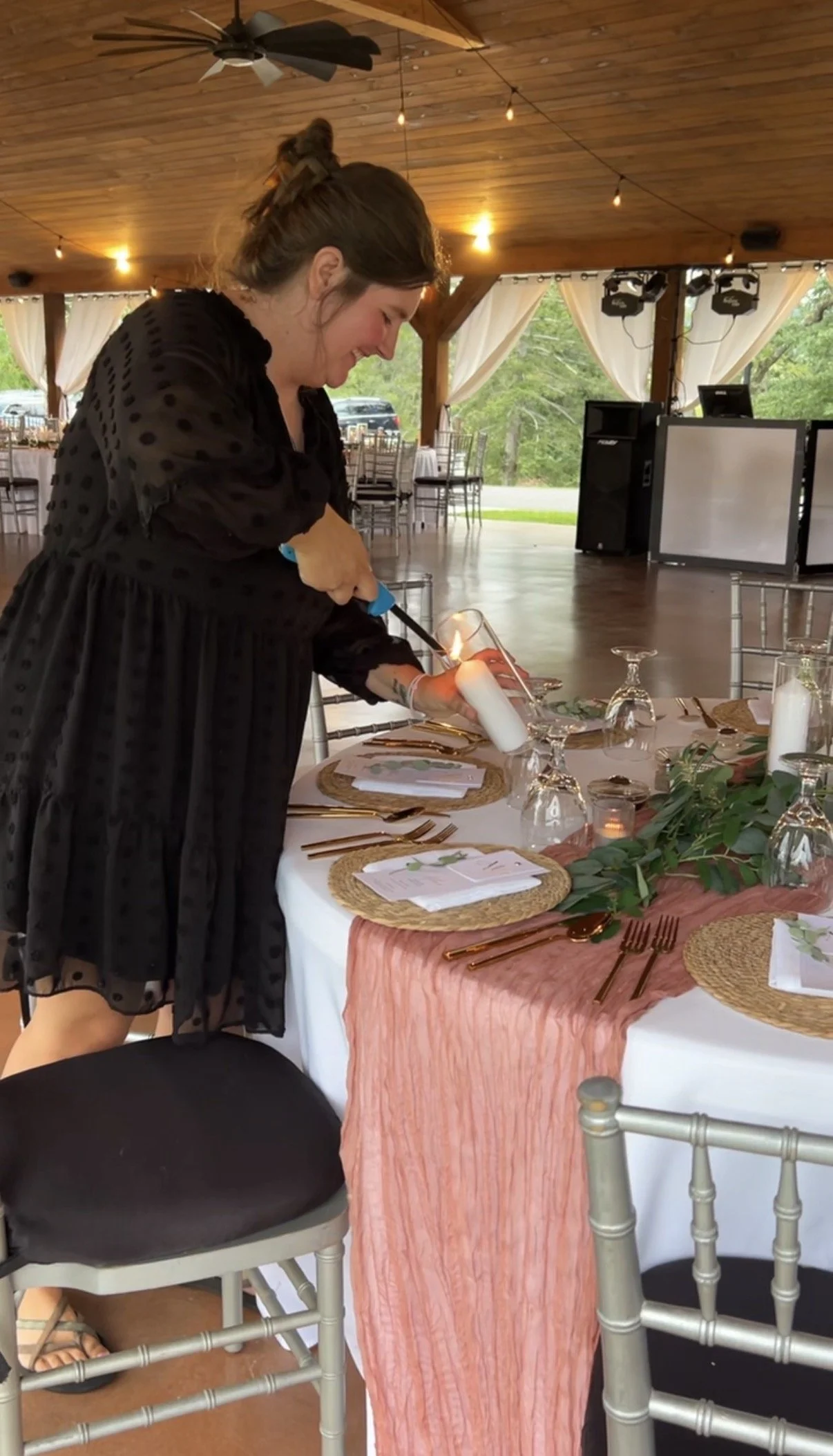 The wedding planner and coordinator lights candles at the wedding reception table.